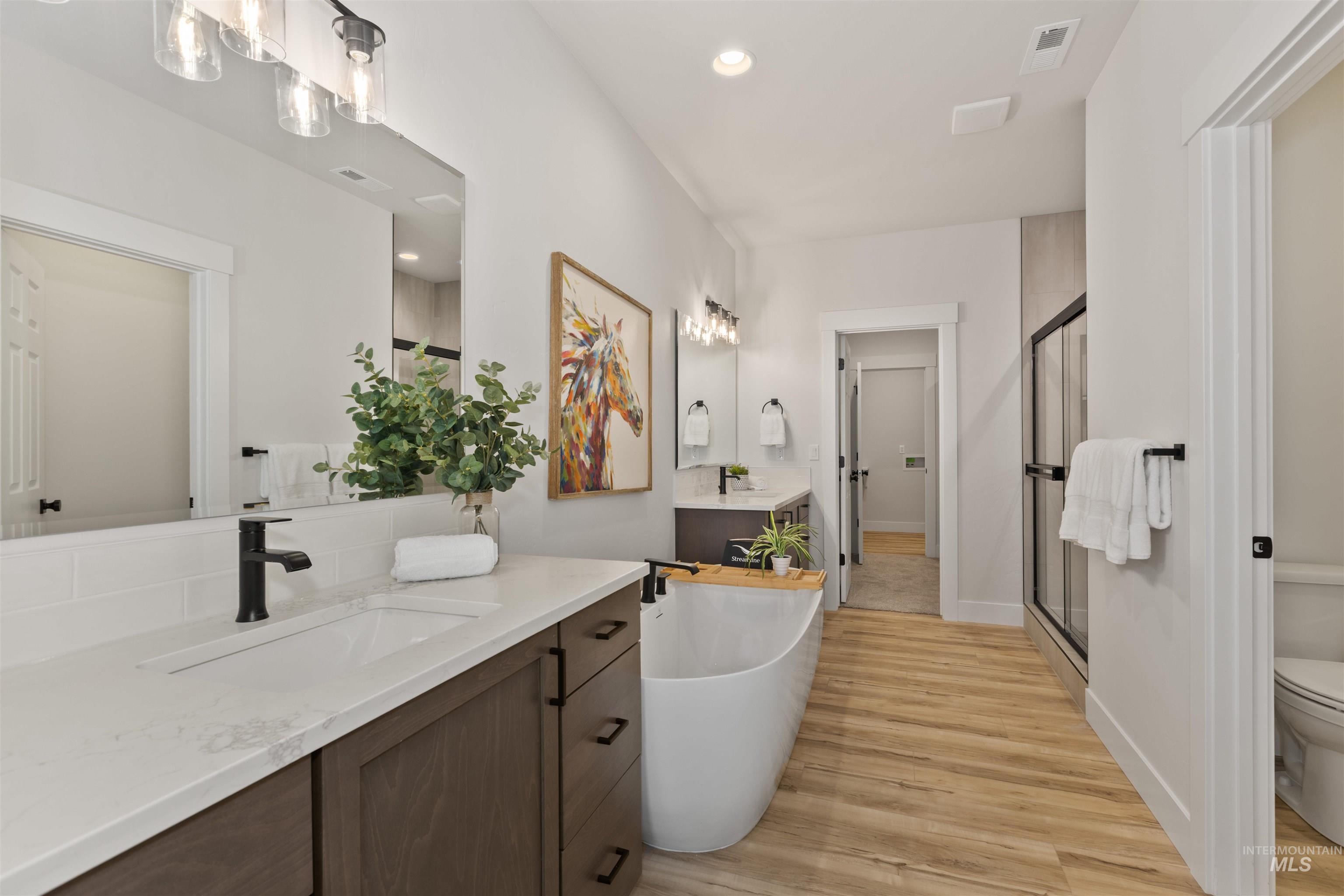 Full bath with a shower stall, a soaking tub, light wood-style flooring, vanity, and recessed lighting