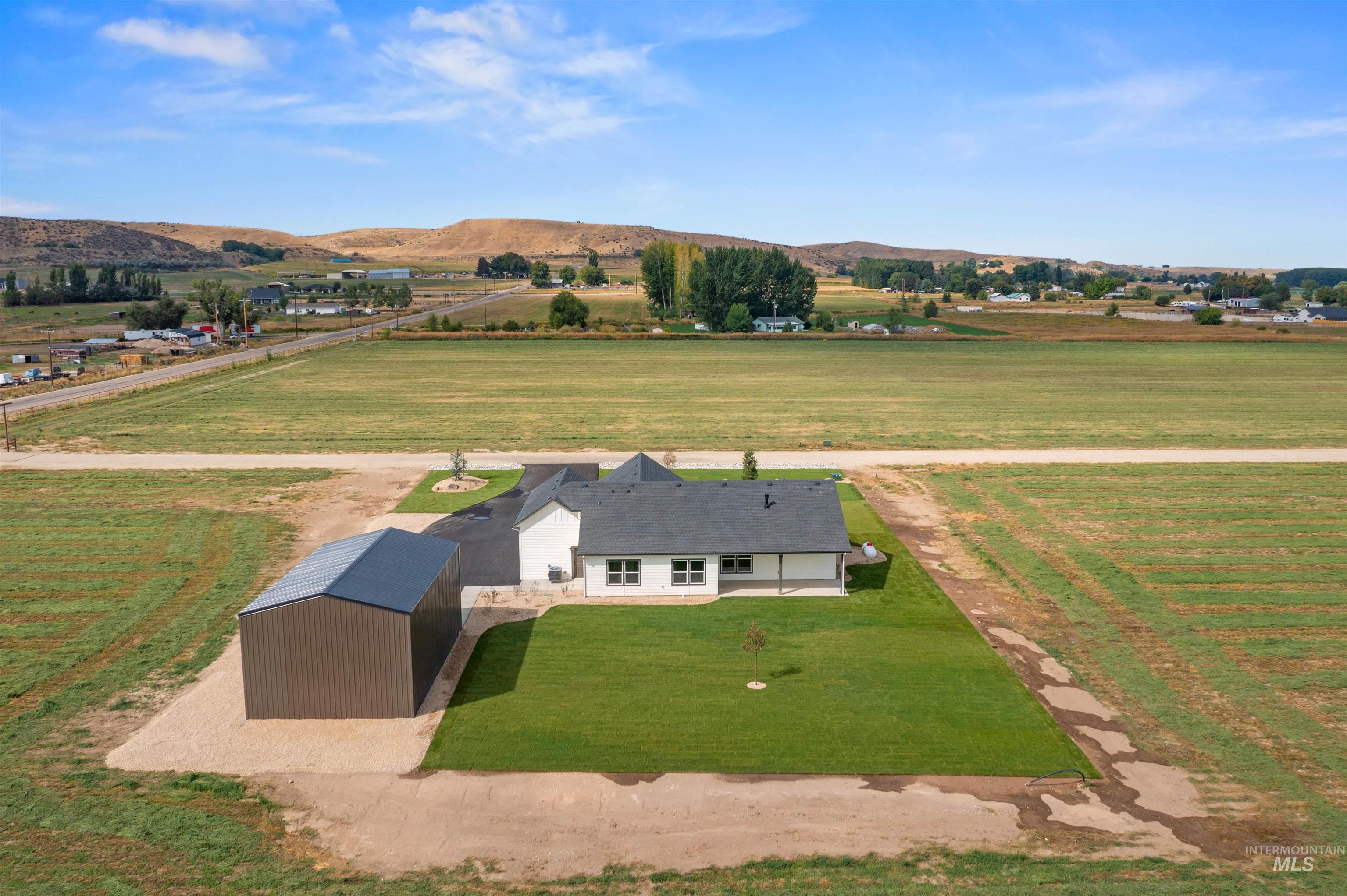 Aerial view of sparsely populated area with a mountain backdrop and rows of crops