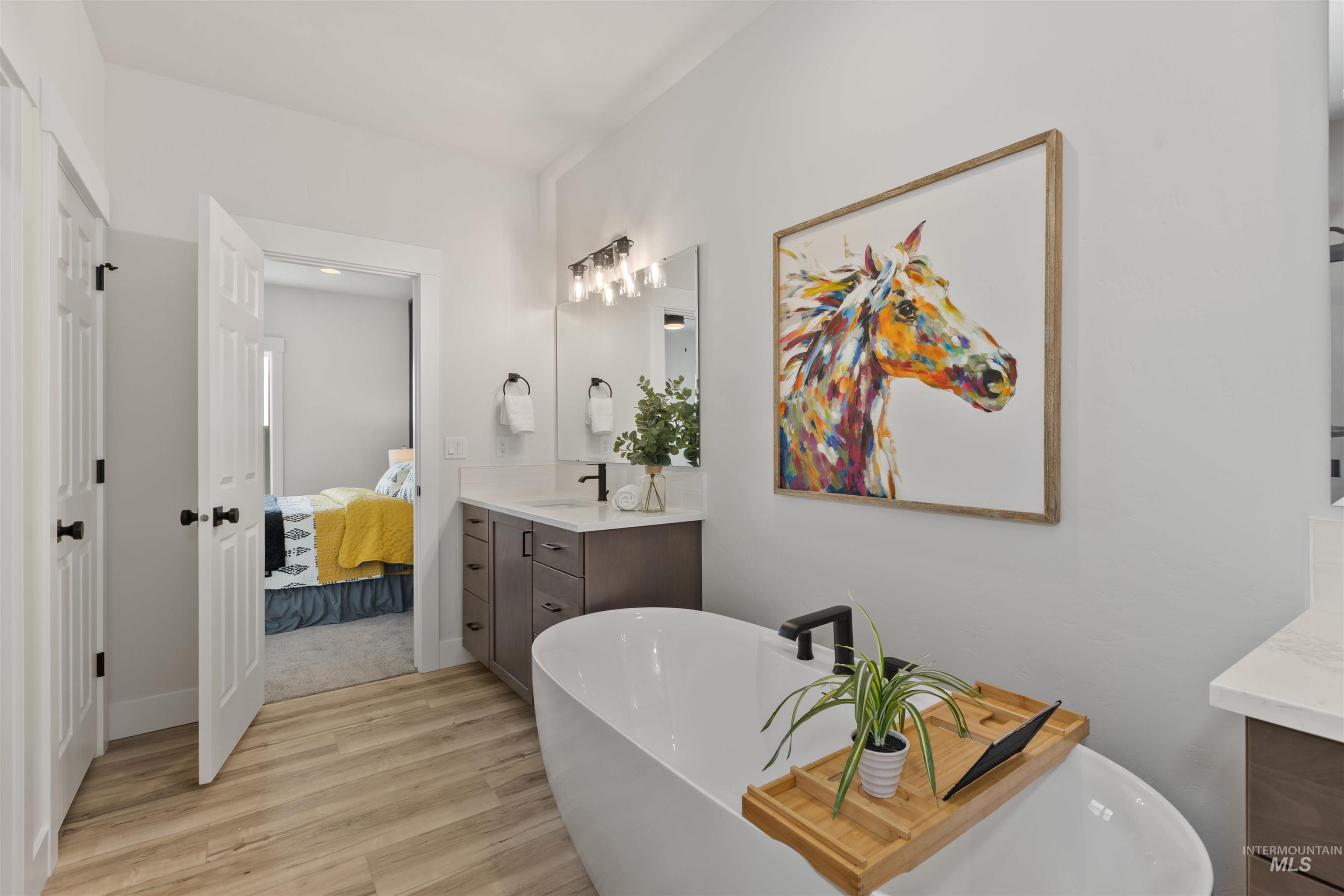 Bathroom featuring a freestanding tub, vanity, light wood-type flooring, and ensuite bathroom