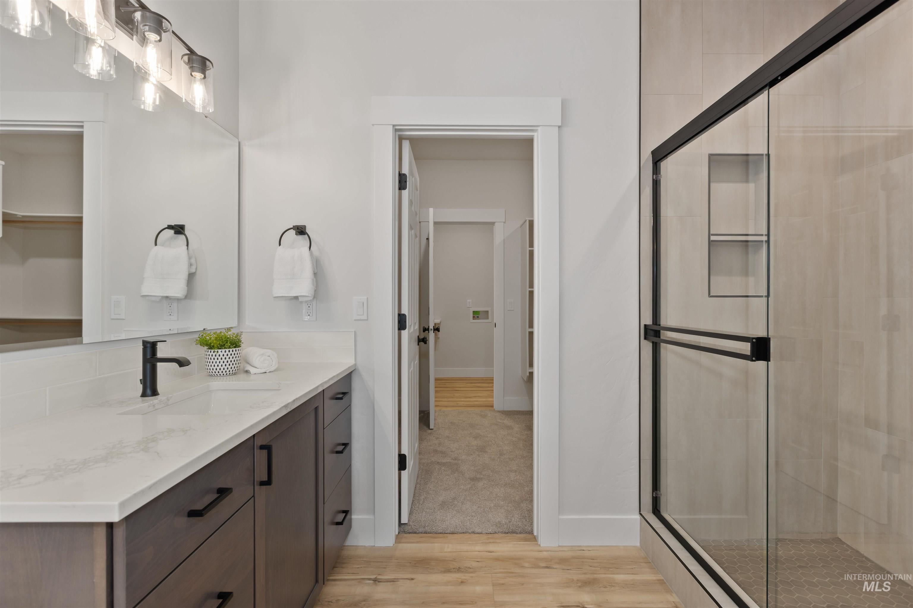 Full bath featuring light wood-style floors, vanity, and a stall shower