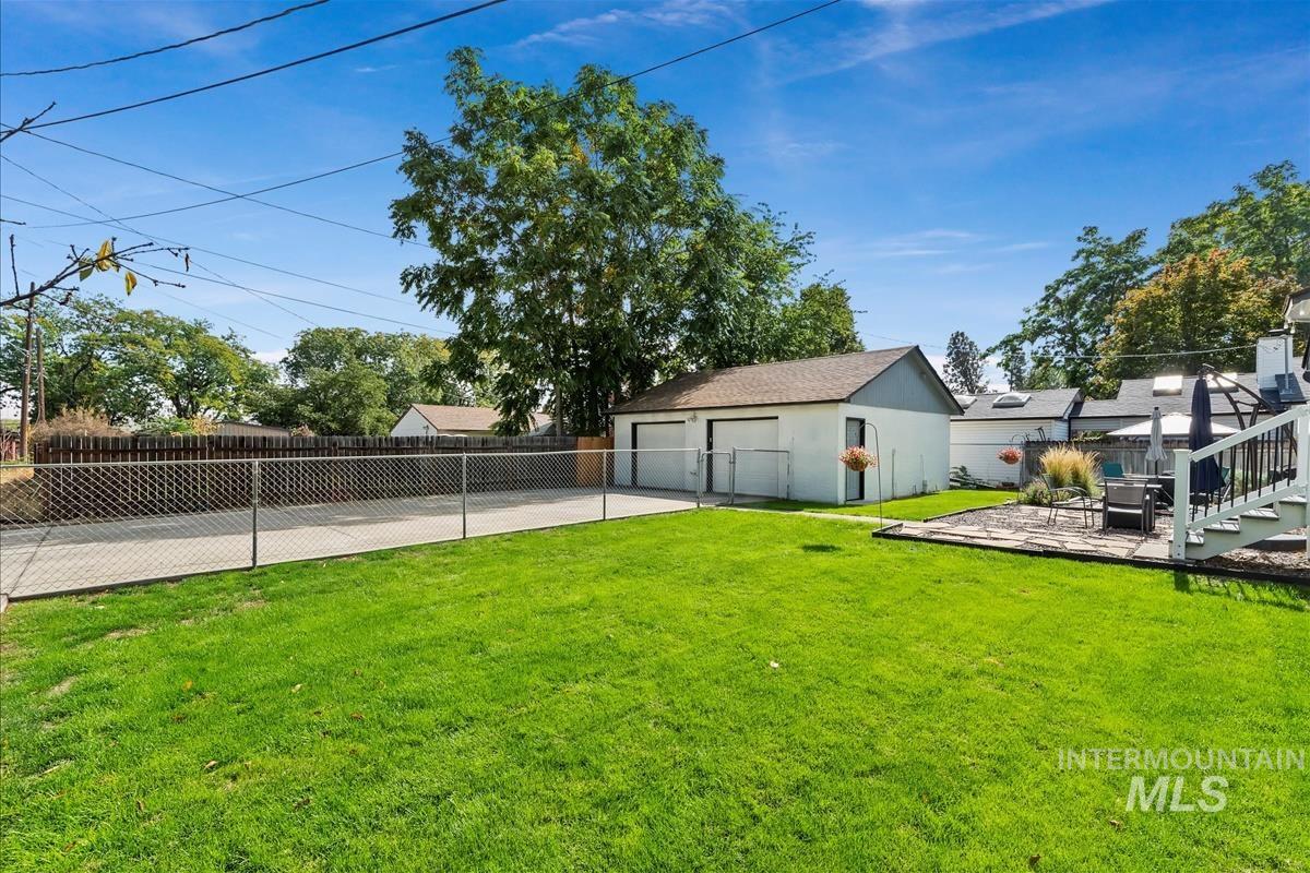 Fenced backyard featuring an outbuilding, a patio area, and a garage