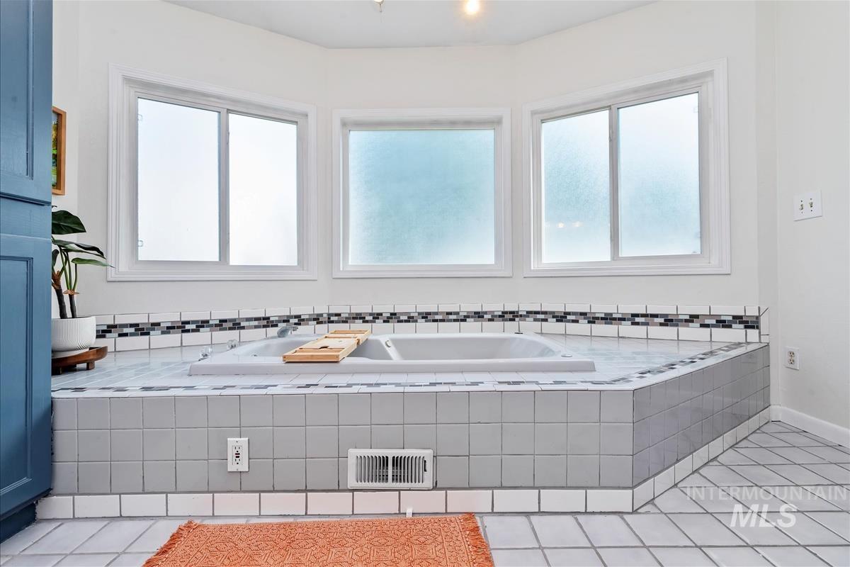 Full bathroom with light tile patterned floors and a garden tub