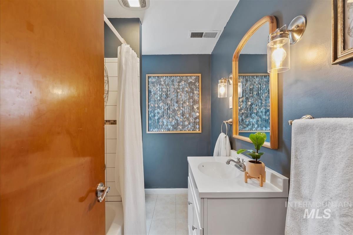 Full bathroom featuring shower / bath combo, vanity, and light tile patterned floors