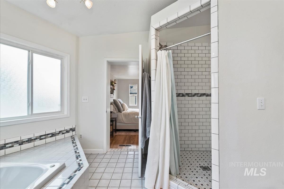Bathroom featuring a shower stall, light tile patterned flooring, a bath, and ensuite bathroom