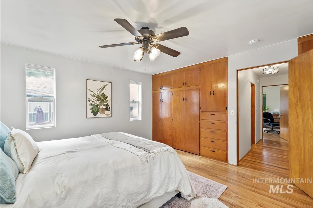 Bedroom featuring light wood-style floors, multiple windows, a closet, and ceiling fan