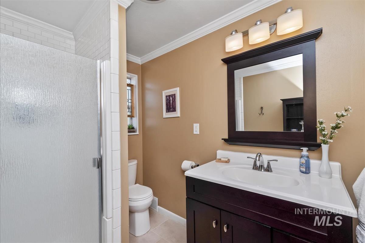 Bathroom featuring a stall shower, vanity, light tile patterned flooring, and ornamental molding