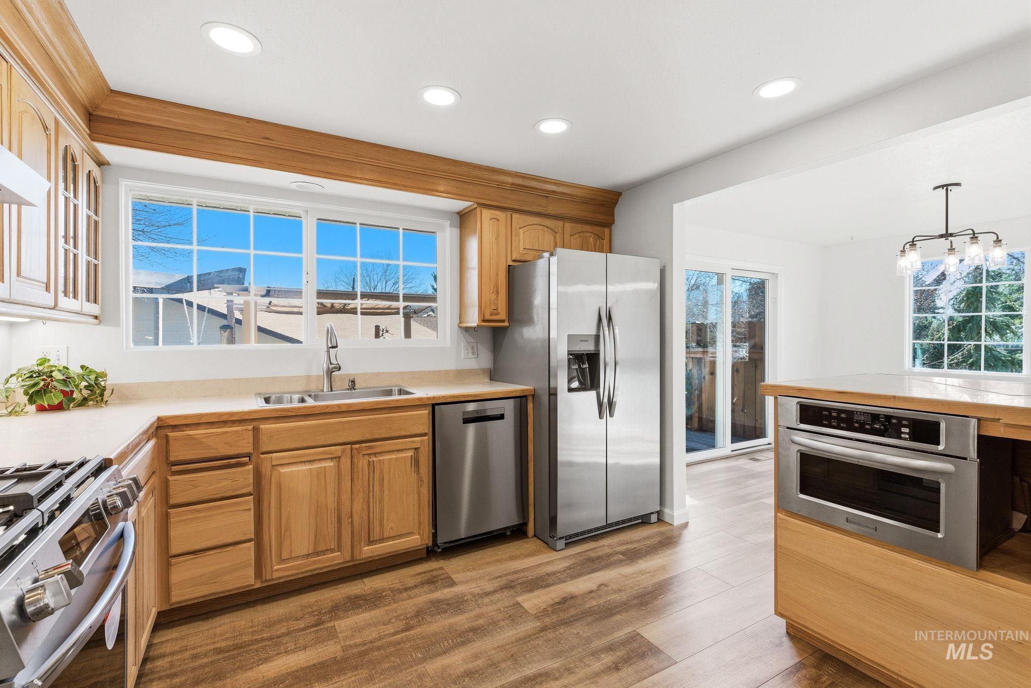 Kitchen with light countertops, stainless steel appliances, hanging light fixtures, and dark wood-type flooring
