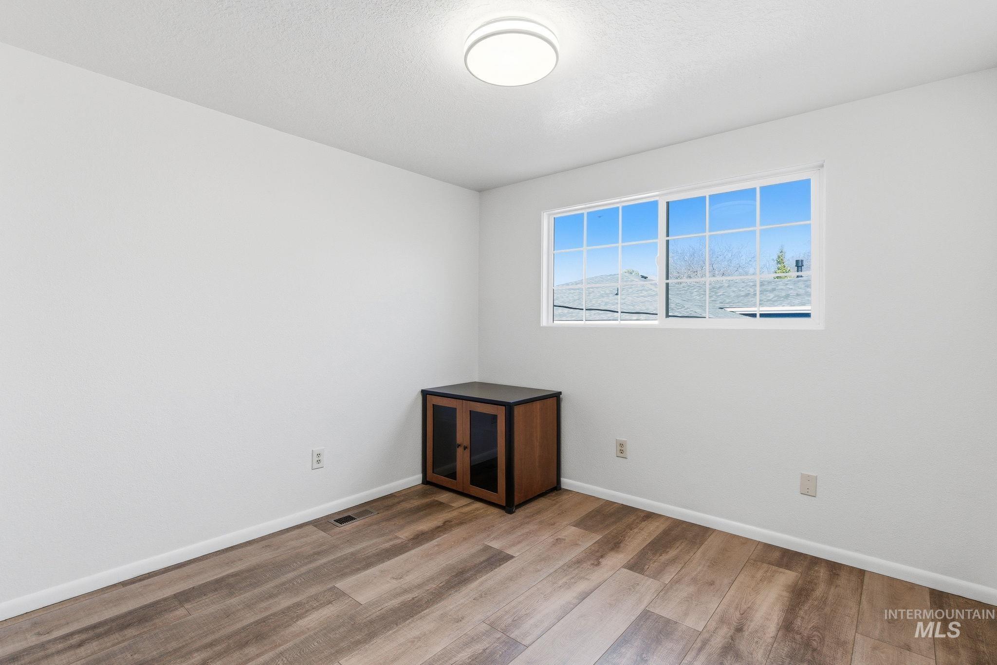 Empty room with light wood finished floors and a textured ceiling