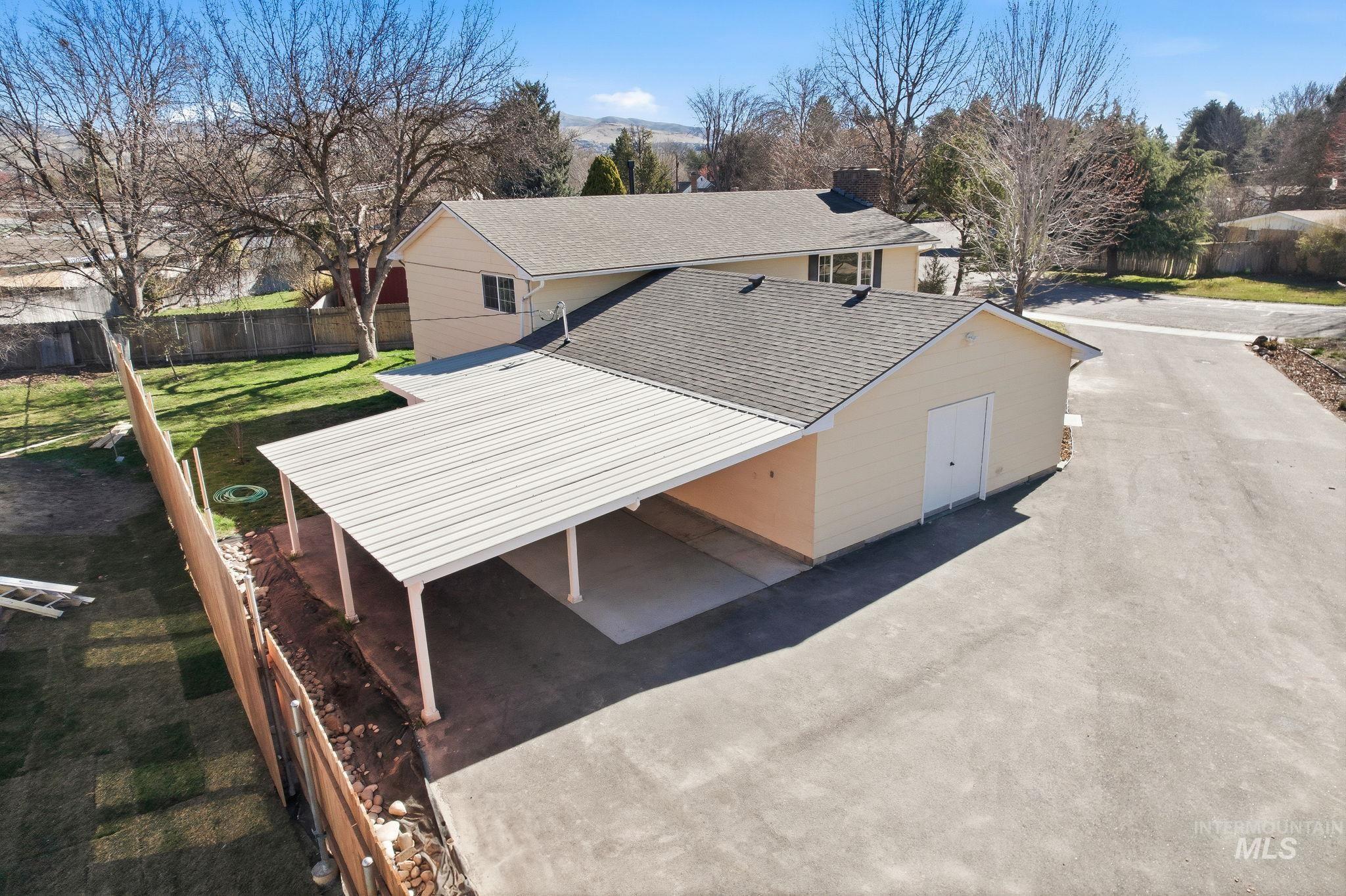 View of front facade featuring a shingled roof and a carport