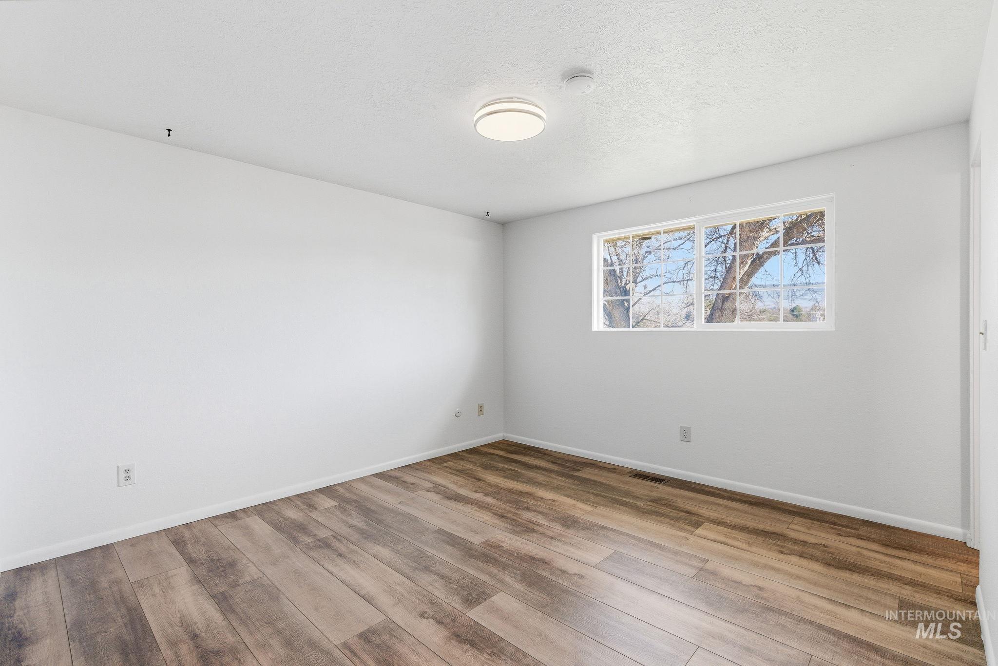 Empty room featuring light wood-style floors and a textured ceiling