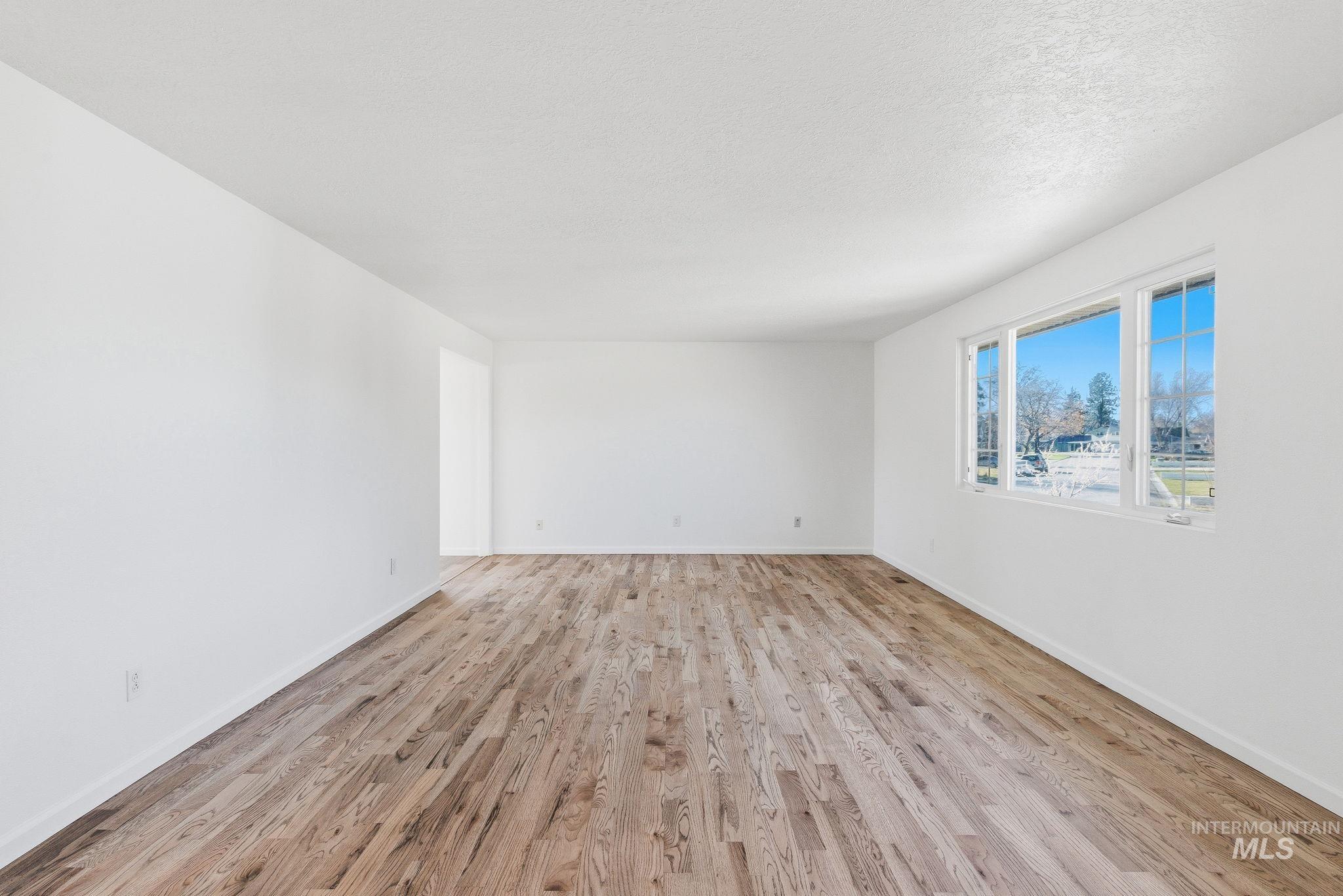 Empty room with light wood-style floors and a textured ceiling