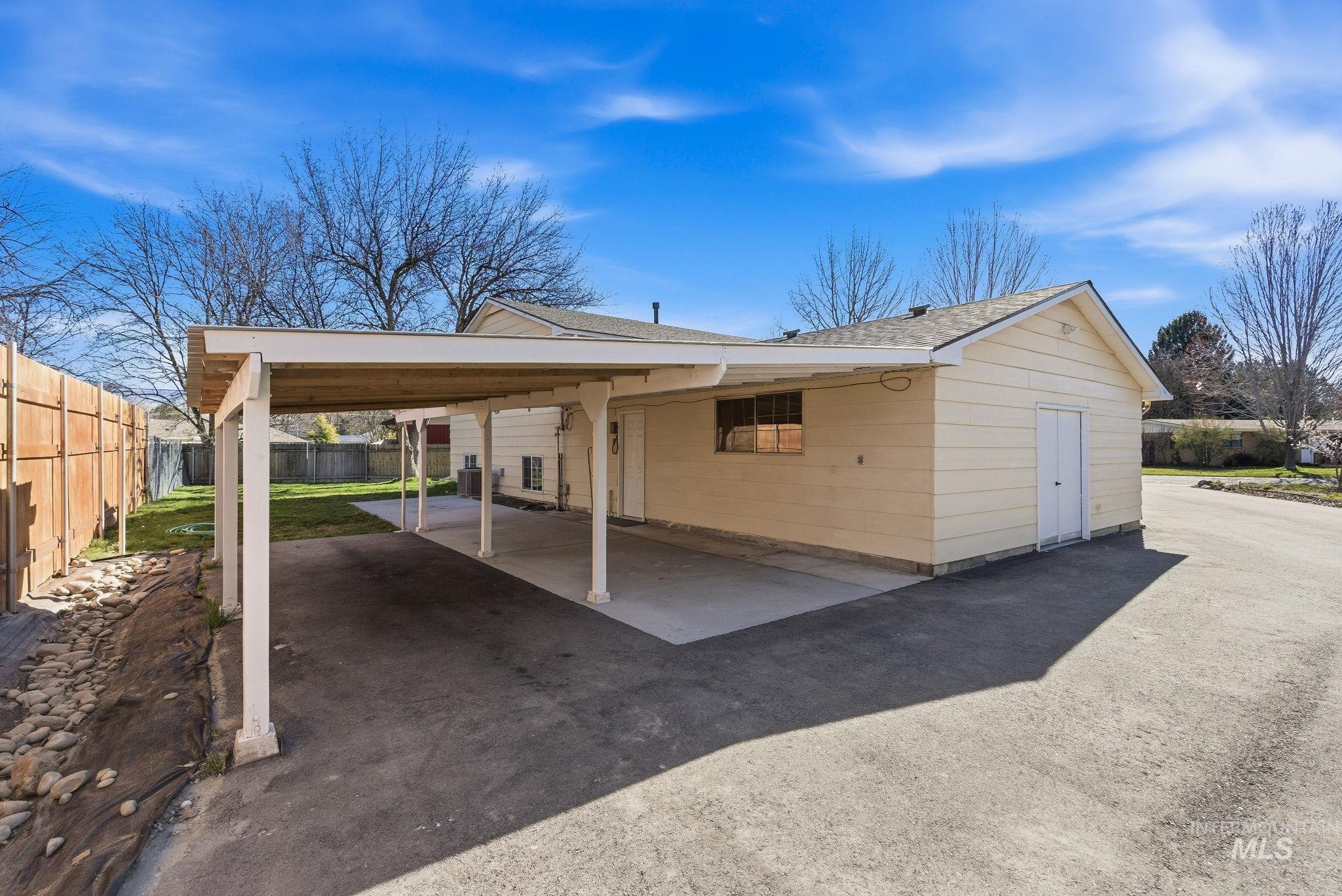 View of front of home with a patio area, a carport, driveway, and roof with shingles