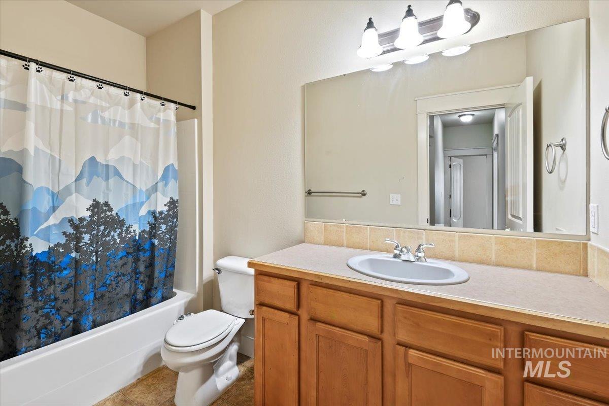 Full bath with shower / bath combination with curtain, vanity, and tile patterned floors