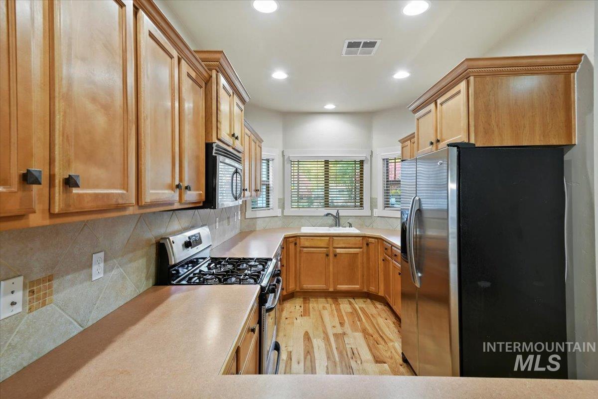 Kitchen with appliances with stainless steel finishes, light countertops, light wood-style flooring, tasteful backsplash, and recessed lighting