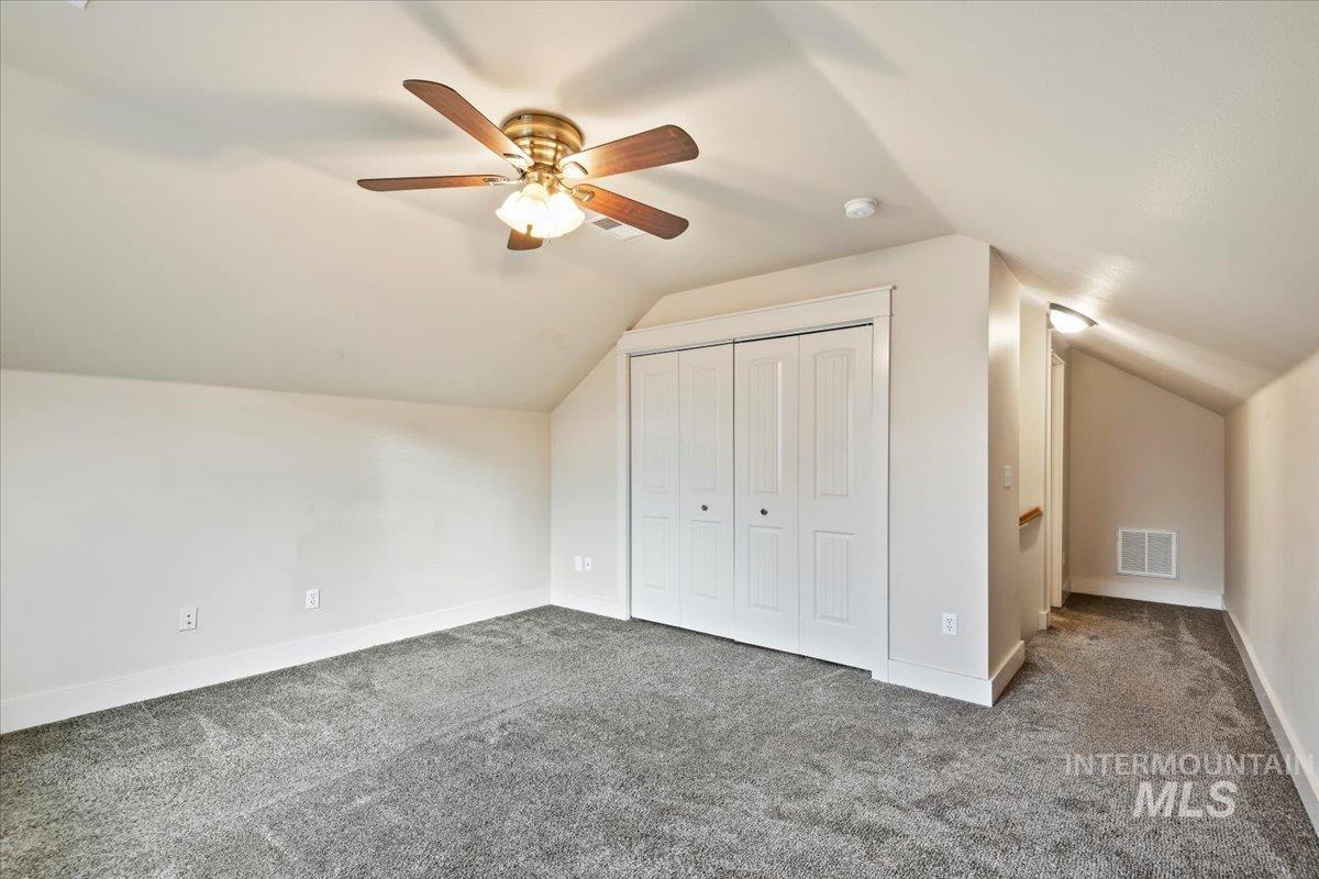 Bonus room featuring vaulted ceiling, carpet flooring, and a ceiling fan