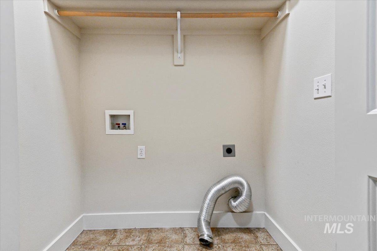 Laundry area with electric dryer hookup, hookup for a washing machine, and light tile patterned floors