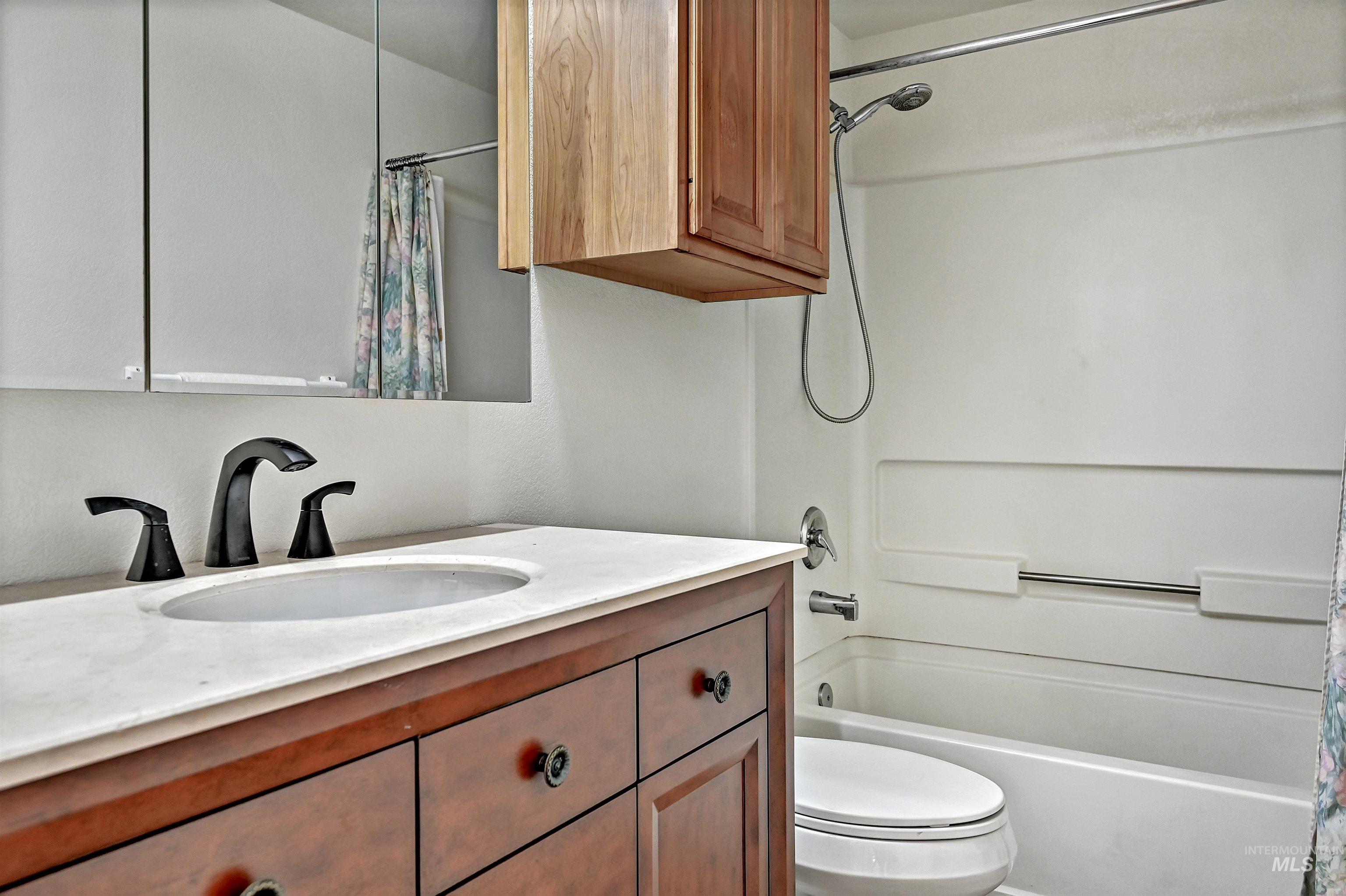 Bathroom with shower / tub combo with curtain and vanity