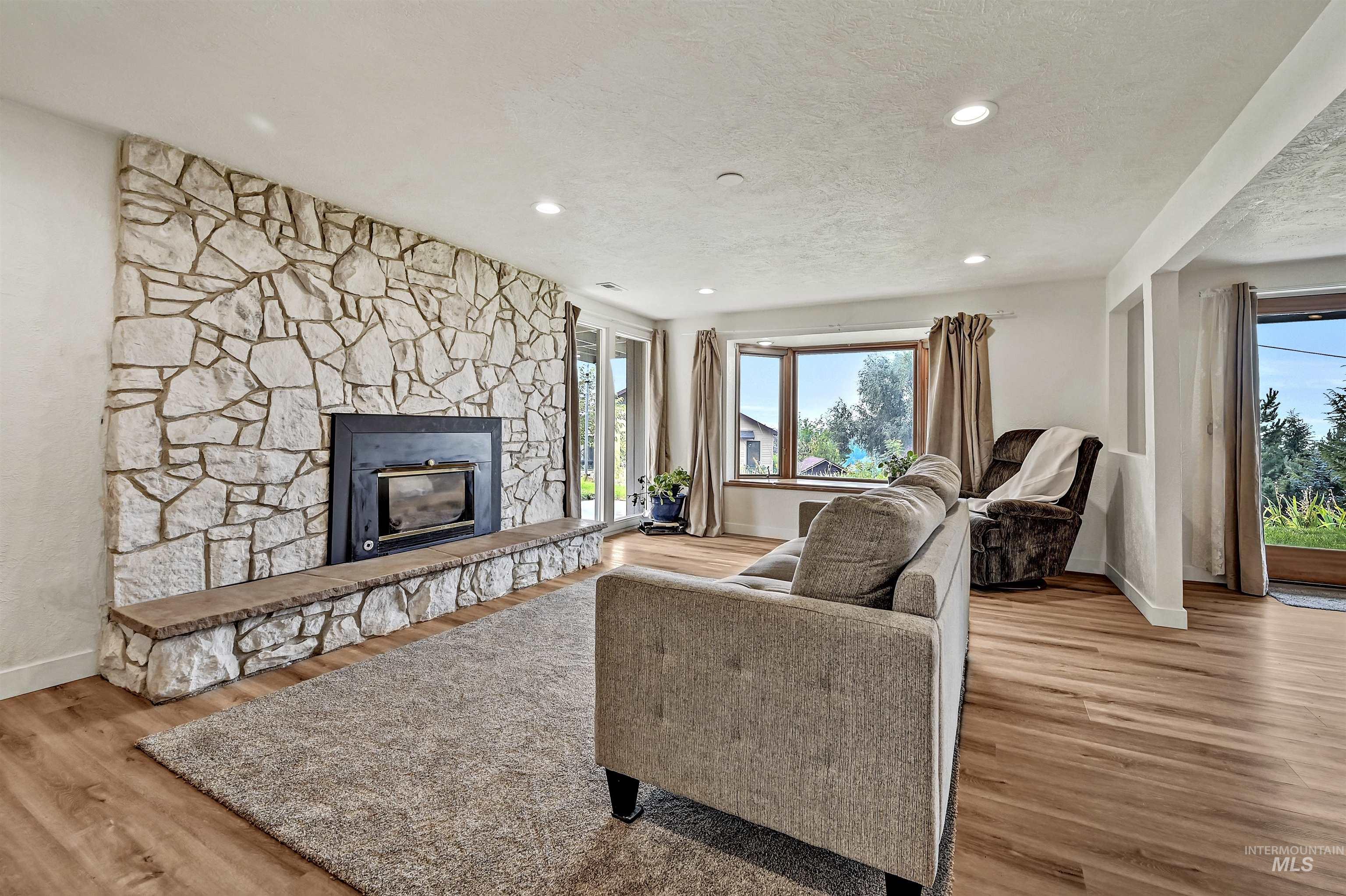 Living area with a fireplace, recessed lighting, light wood-type flooring, and a textured ceiling