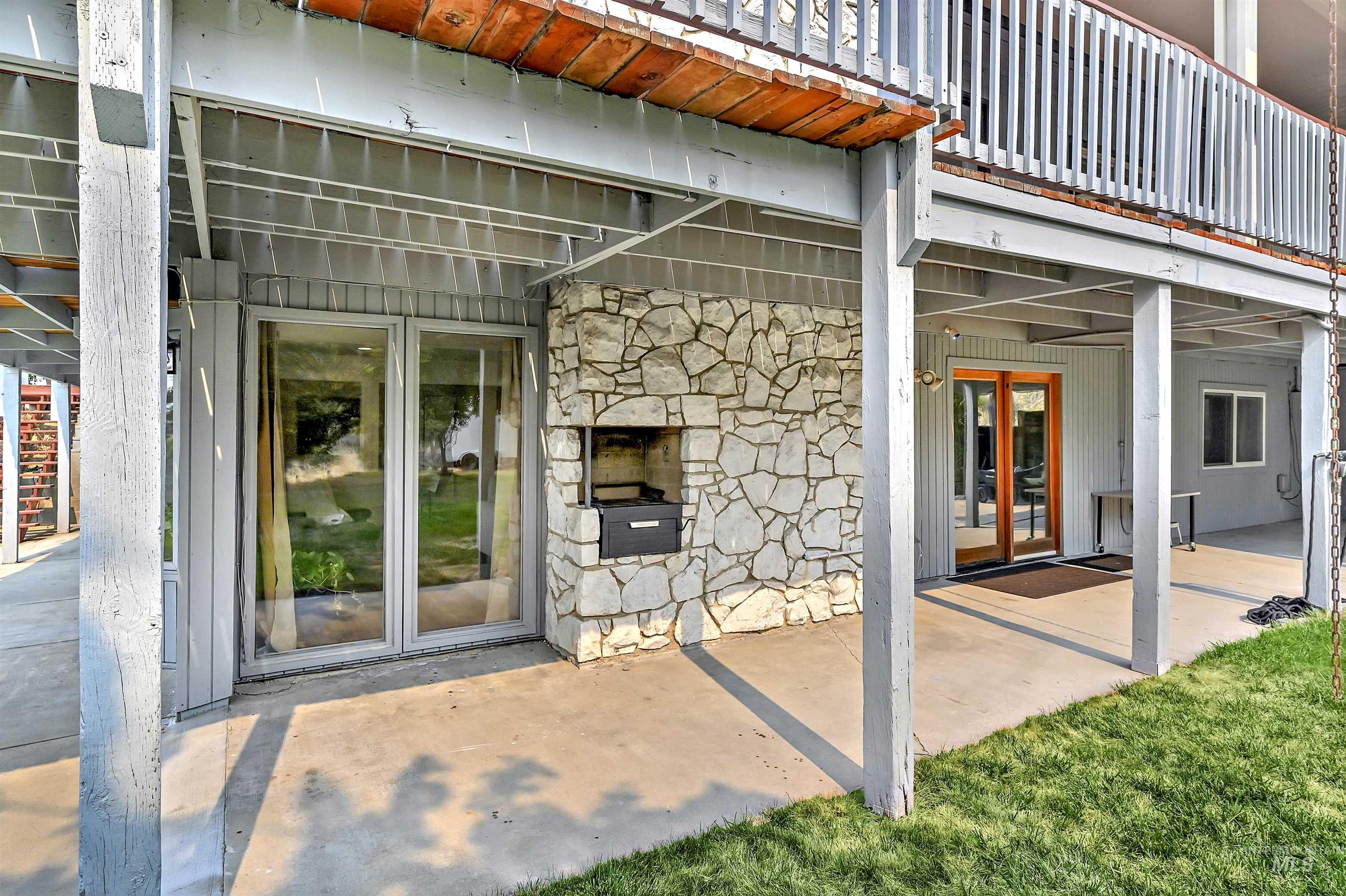 Property entrance with stone siding, a patio, and a lawn