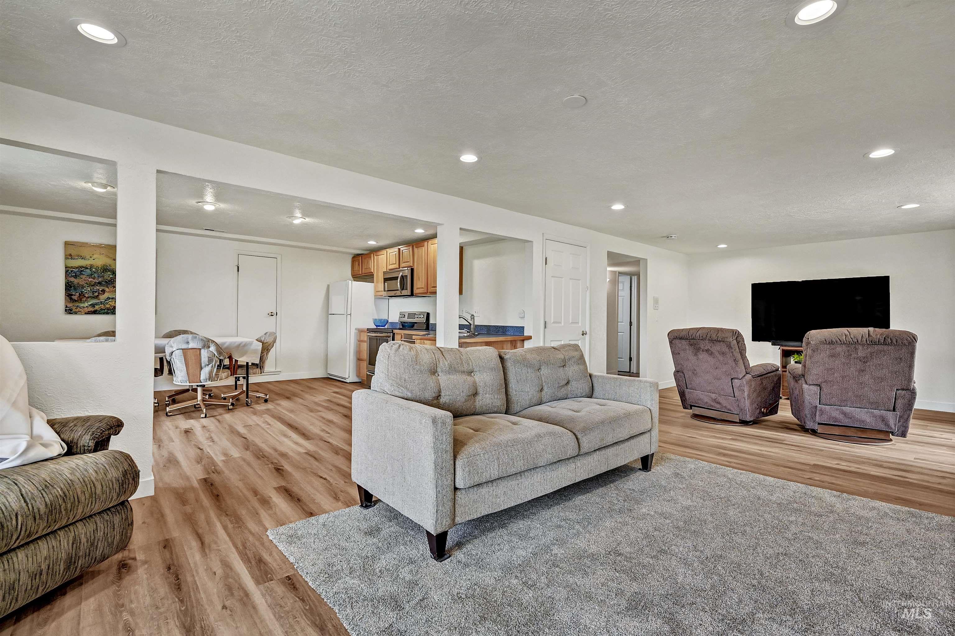 Living area with recessed lighting, light wood-type flooring, and a textured ceiling