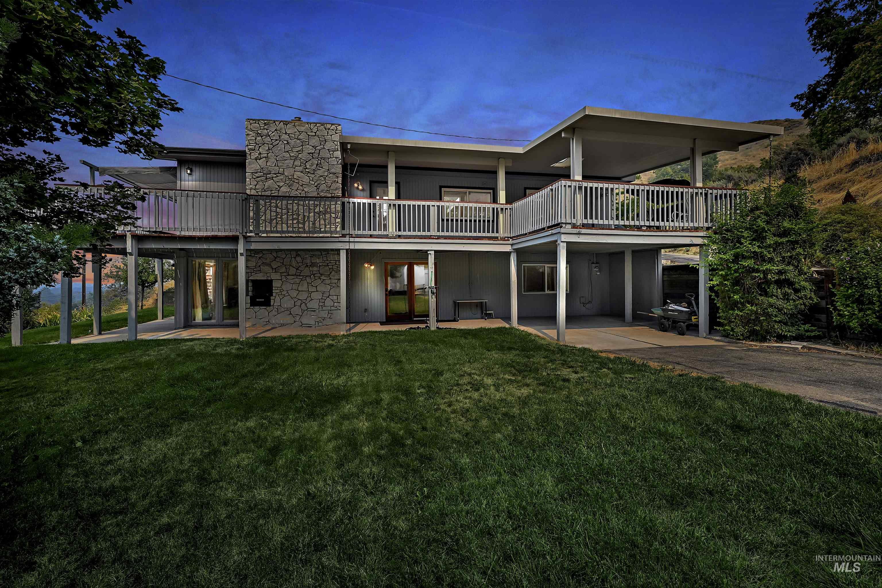 Back of house featuring a yard, stone siding, and a patio area