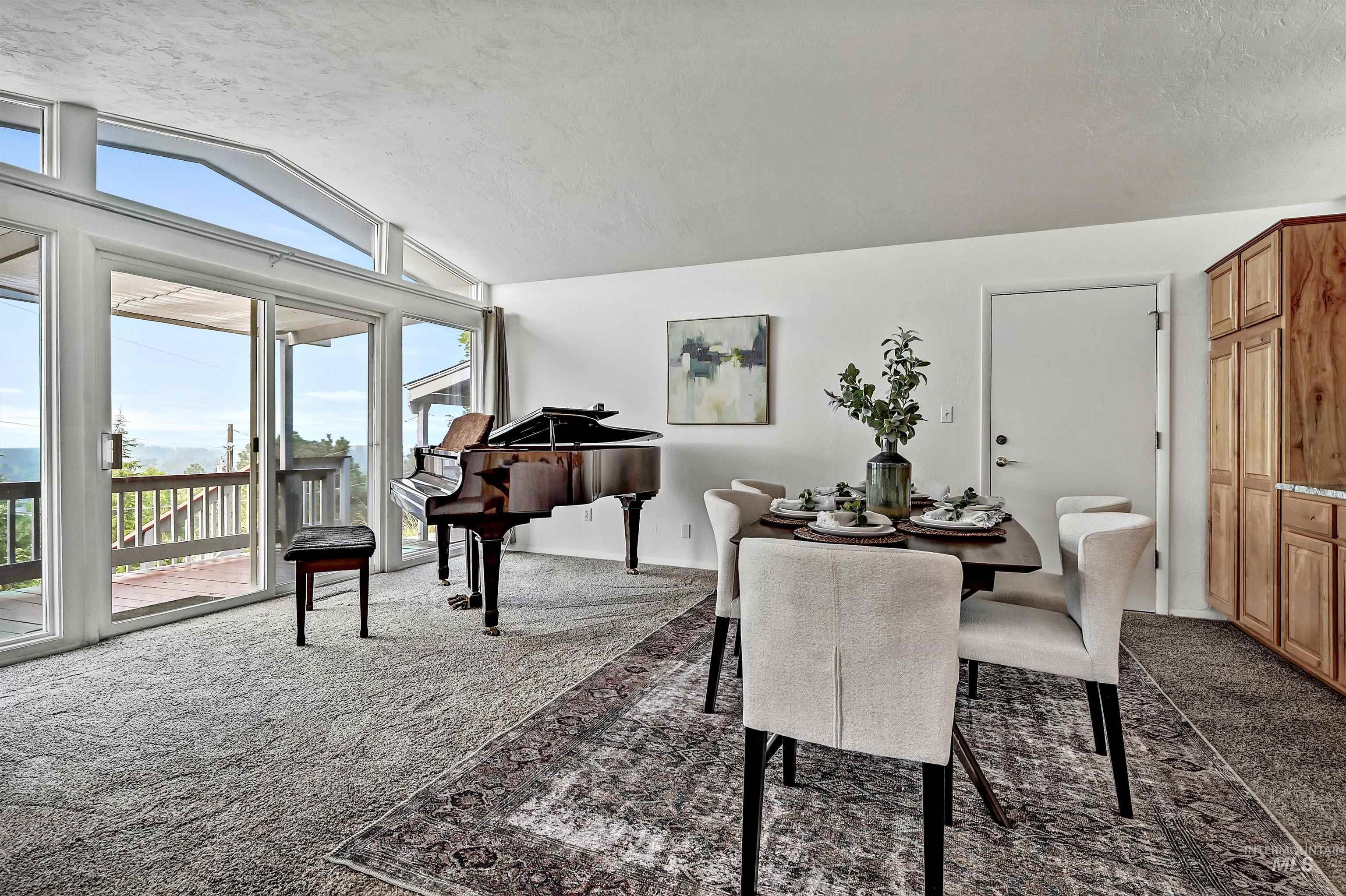 Dining space with lofted ceiling, dark colored carpet, and a textured ceiling