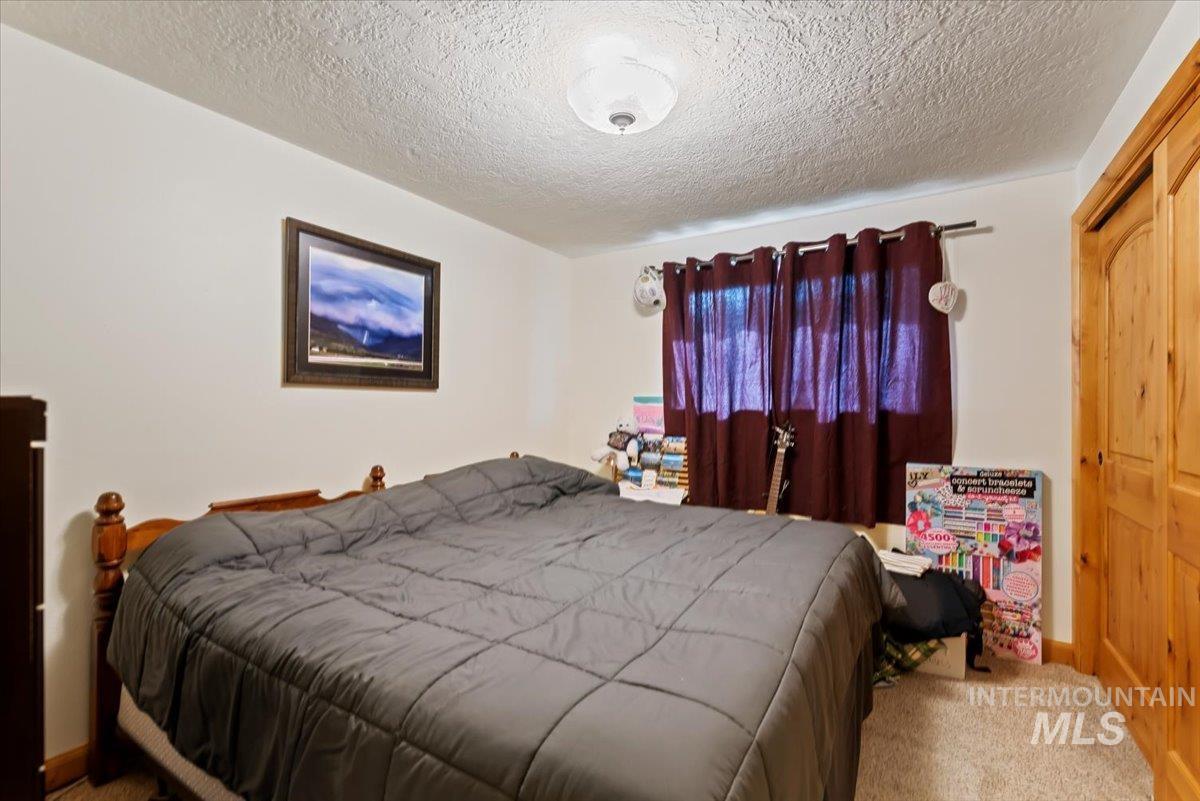 Carpeted bedroom featuring a textured ceiling and baseboards