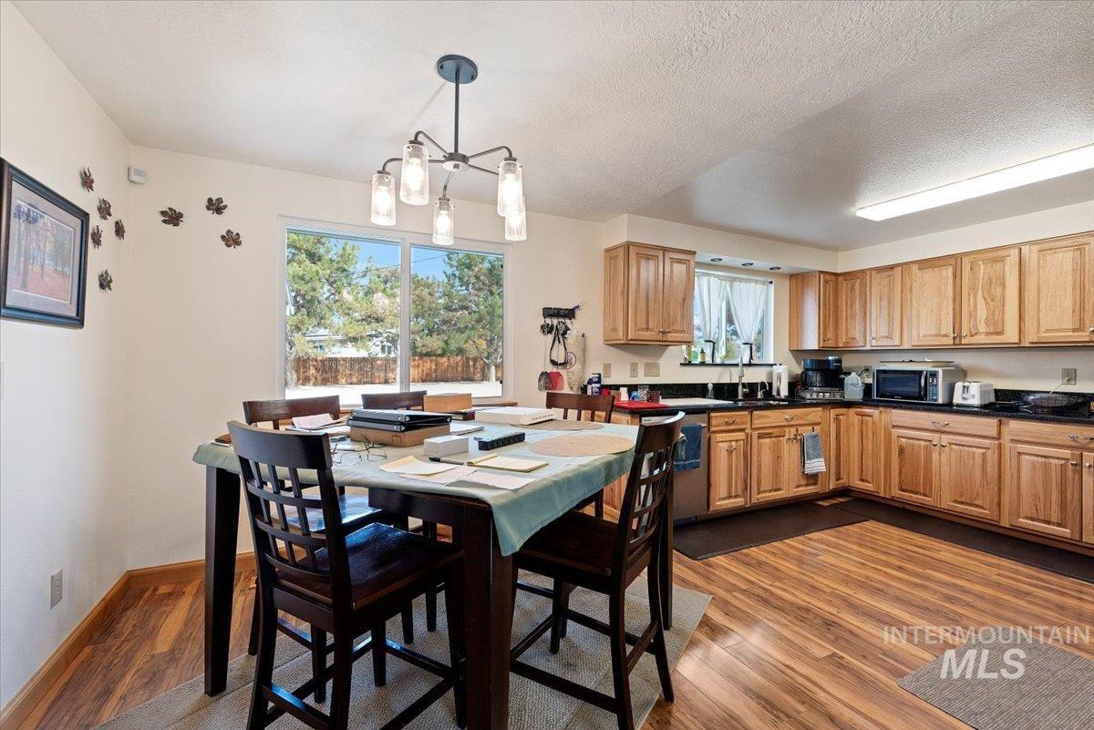 Kitchen featuring dark wood-style flooring, hanging light fixtures, appliances with stainless steel finishes, a textured ceiling, and a chandelier