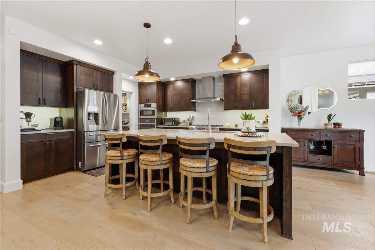 Kitchen featuring dark wood finish cabinets, stainless steel appliances, a breakfast bar area, and light wood-type flooring