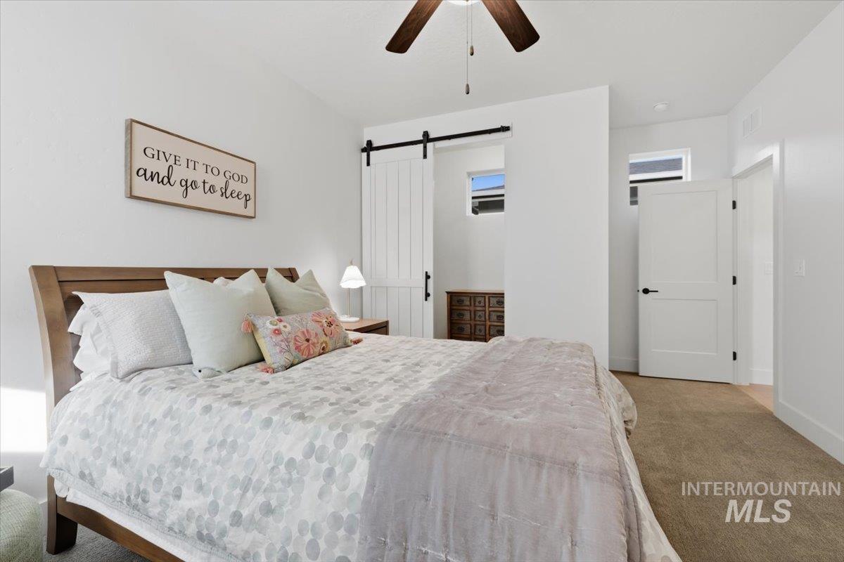 Bedroom with carpet floors, a barn door, and a ceiling fan