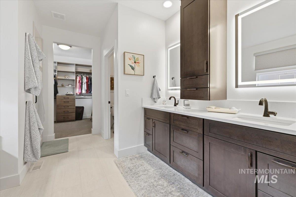 Full bathroom featuring a walk in closet and double vanity
