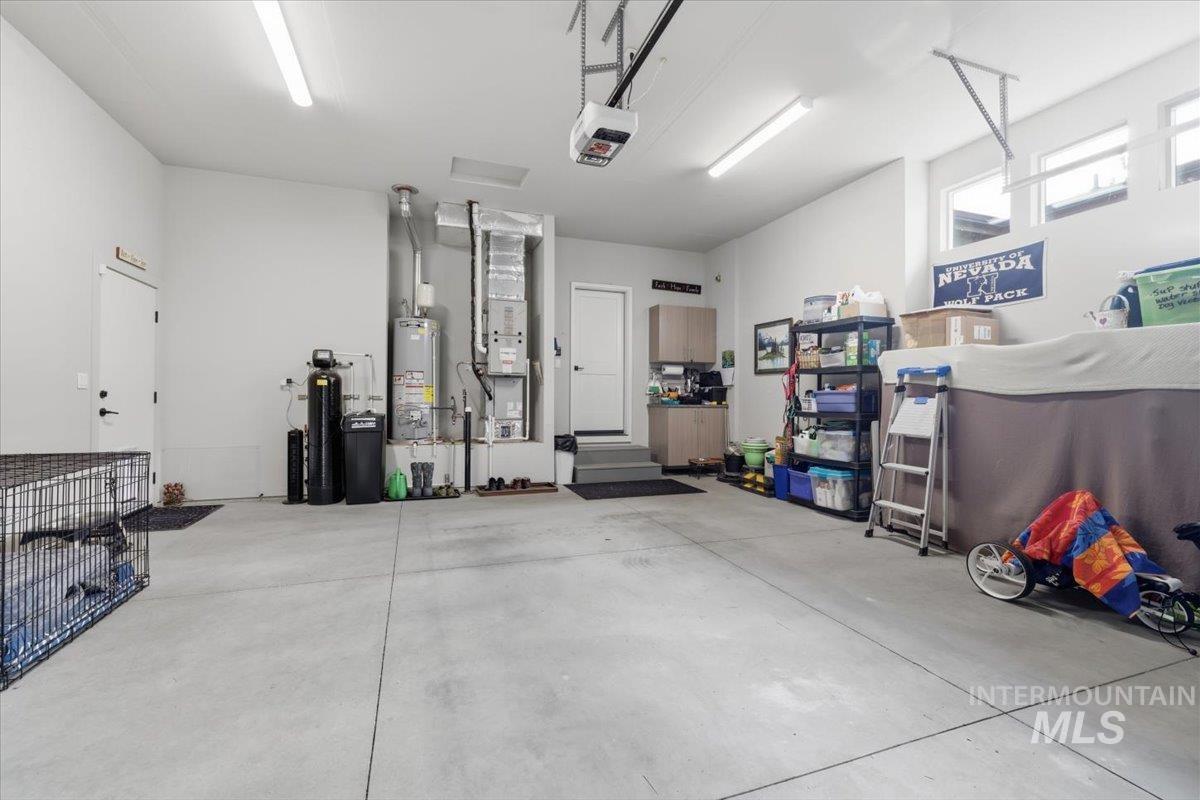 Garage featuring gas water heater, a garage door opener, and heating unit