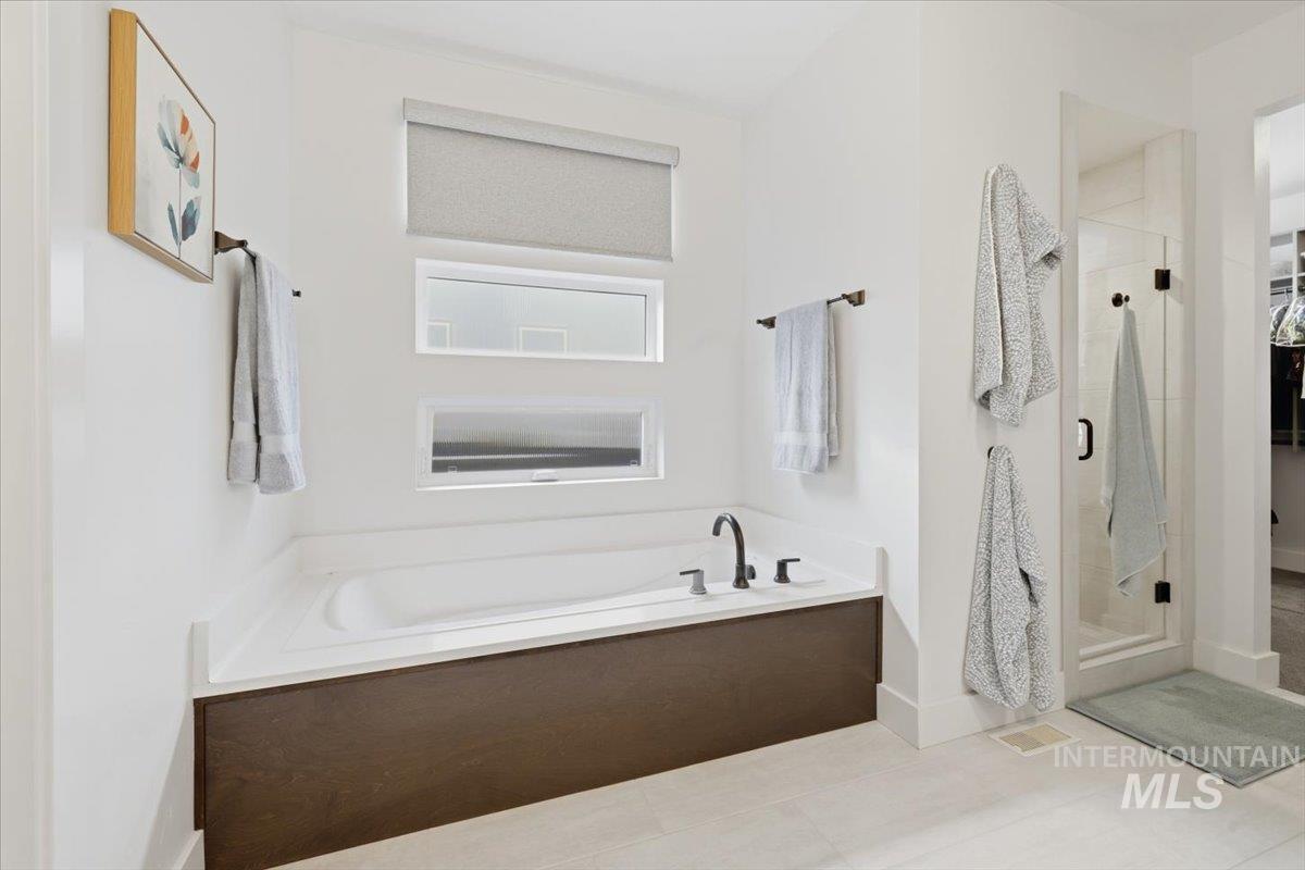 Full bathroom with a stall shower, a bath, light tile patterned floors, and a walk in closet