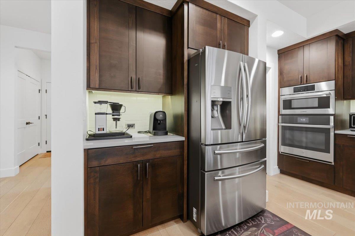 Kitchen with dark wood finish cabinetry, stainless steel appliances, light wood finished floors, light countertops, and recessed lighting