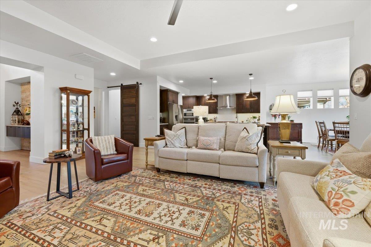 Living room with a barn door, light wood-style floors, recessed lighting, and healthy amount of natural light