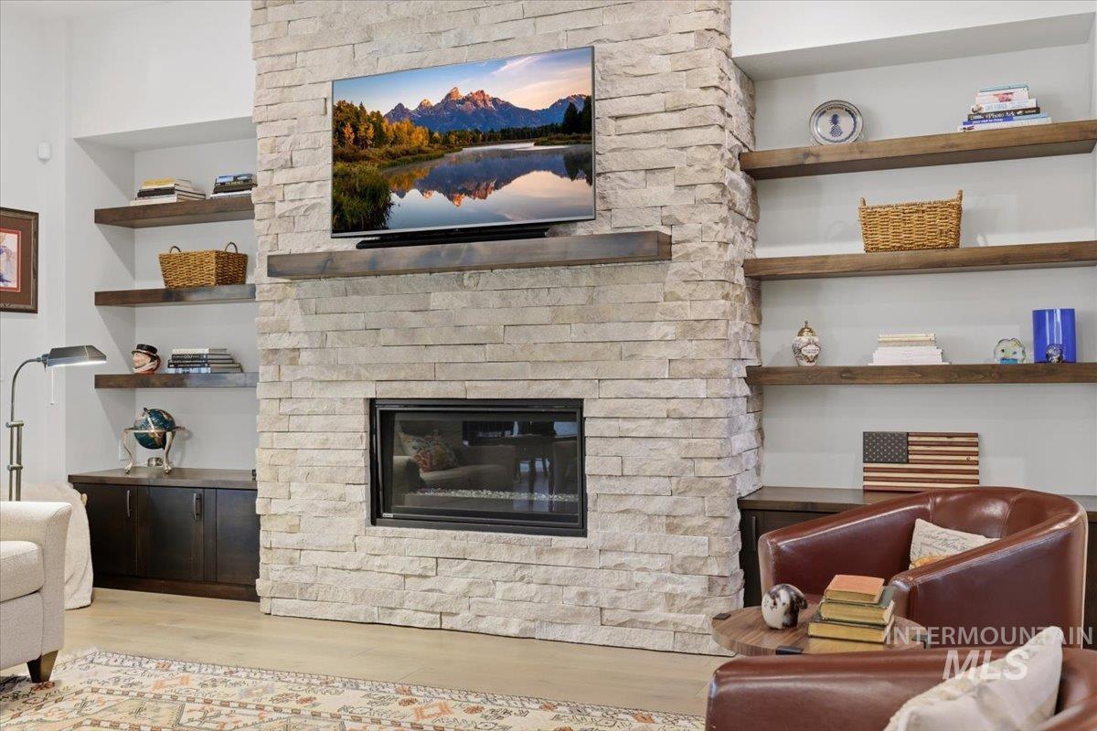 Living room with a fireplace, light wood-style flooring, and built in shelves