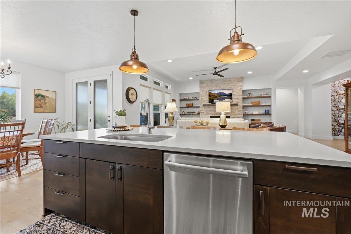 Kitchen with dark wood finish cabinetry, dishwasher, light wood-style floors, and open floor plan