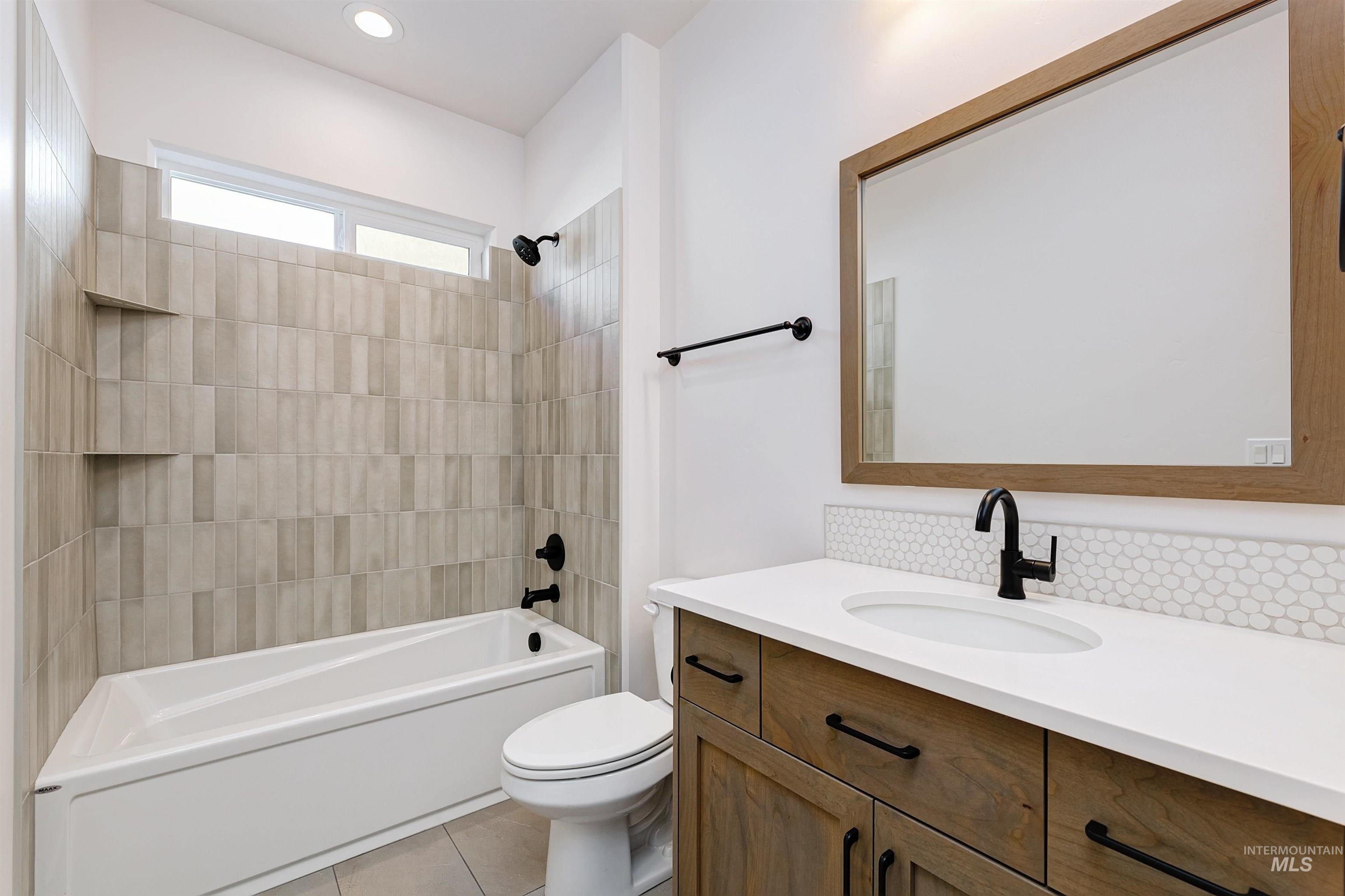 Bathroom featuring washtub / shower combination, vanity, light tile patterned floors, and recessed lighting