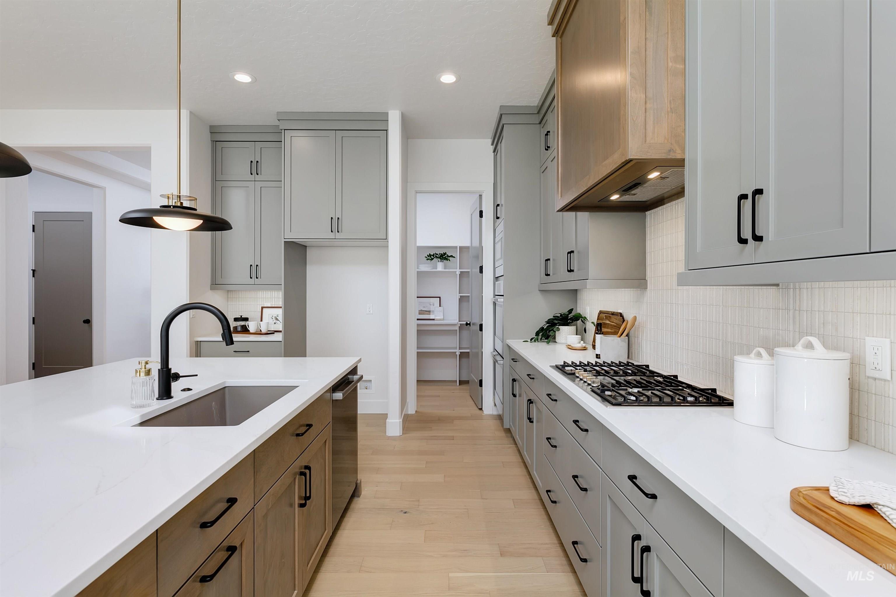 Kitchen with tasteful backsplash, gray cabinets, recessed lighting, light wood-type flooring, and light stone countertops