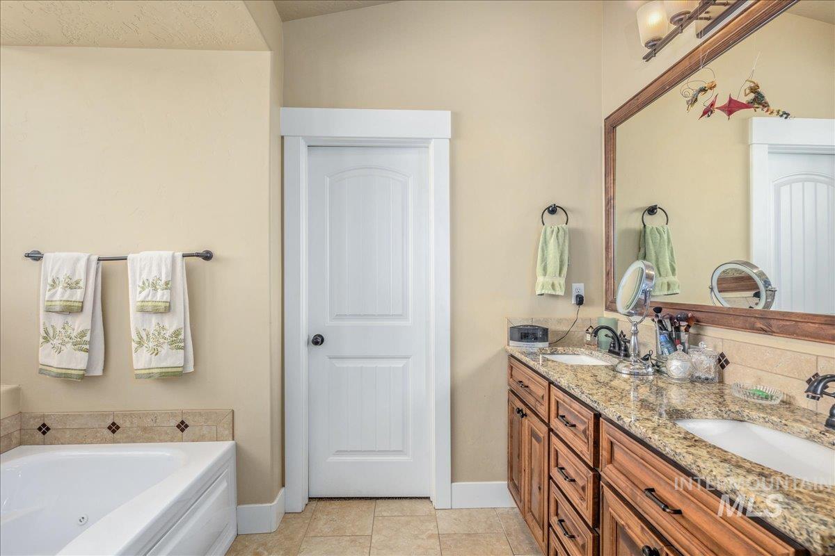 Full bathroom featuring double vanity, a whirlpool tub, and tile patterned flooring