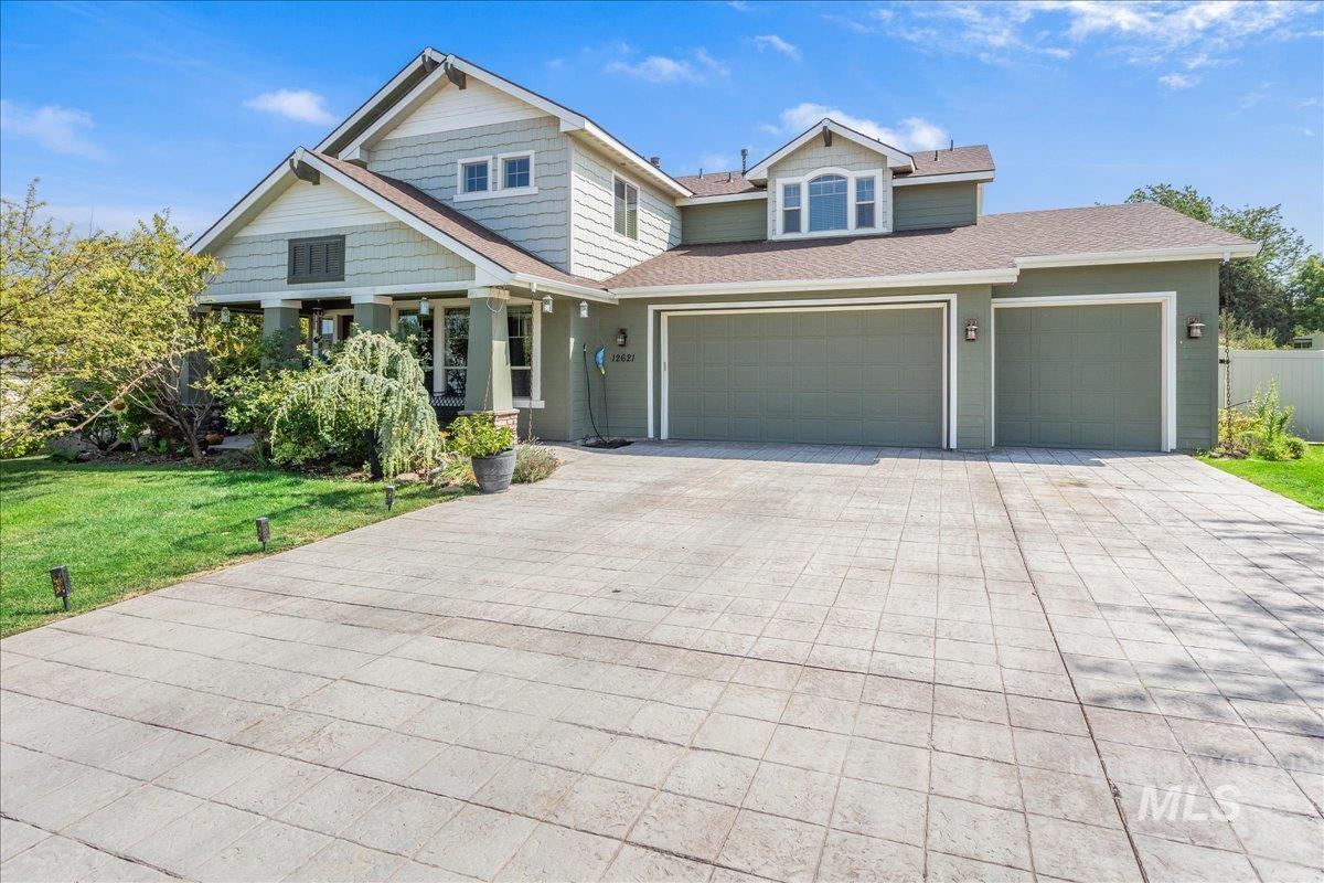 View of front of house featuring decorative driveway, a front lawn, roof with shingles, and a garage