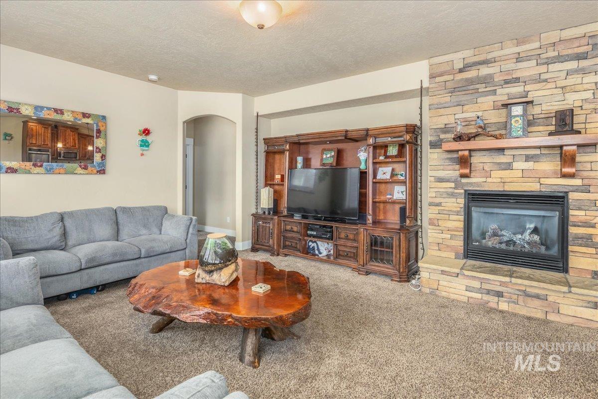 Carpeted living room featuring arched walkways, a textured ceiling, and a fireplace