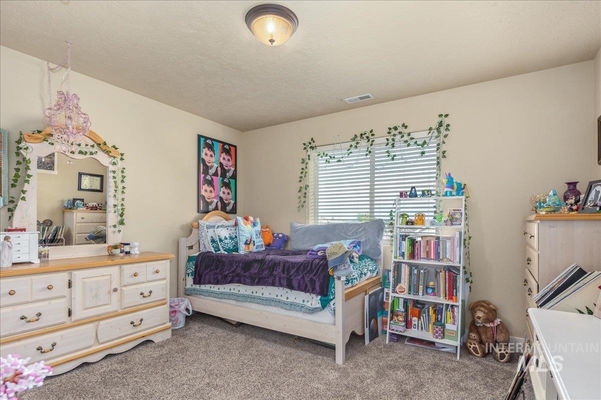Bedroom with light colored carpet and a textured ceiling