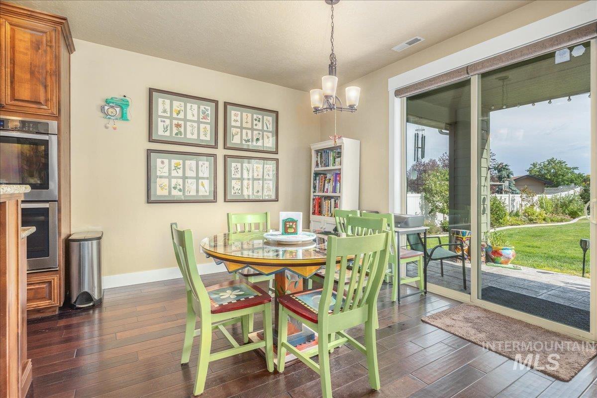 Dining area with dark wood-style flooring and a chandelier