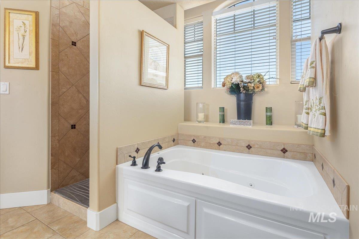 Full bath featuring a whirlpool tub, tiled shower, and tile patterned floors