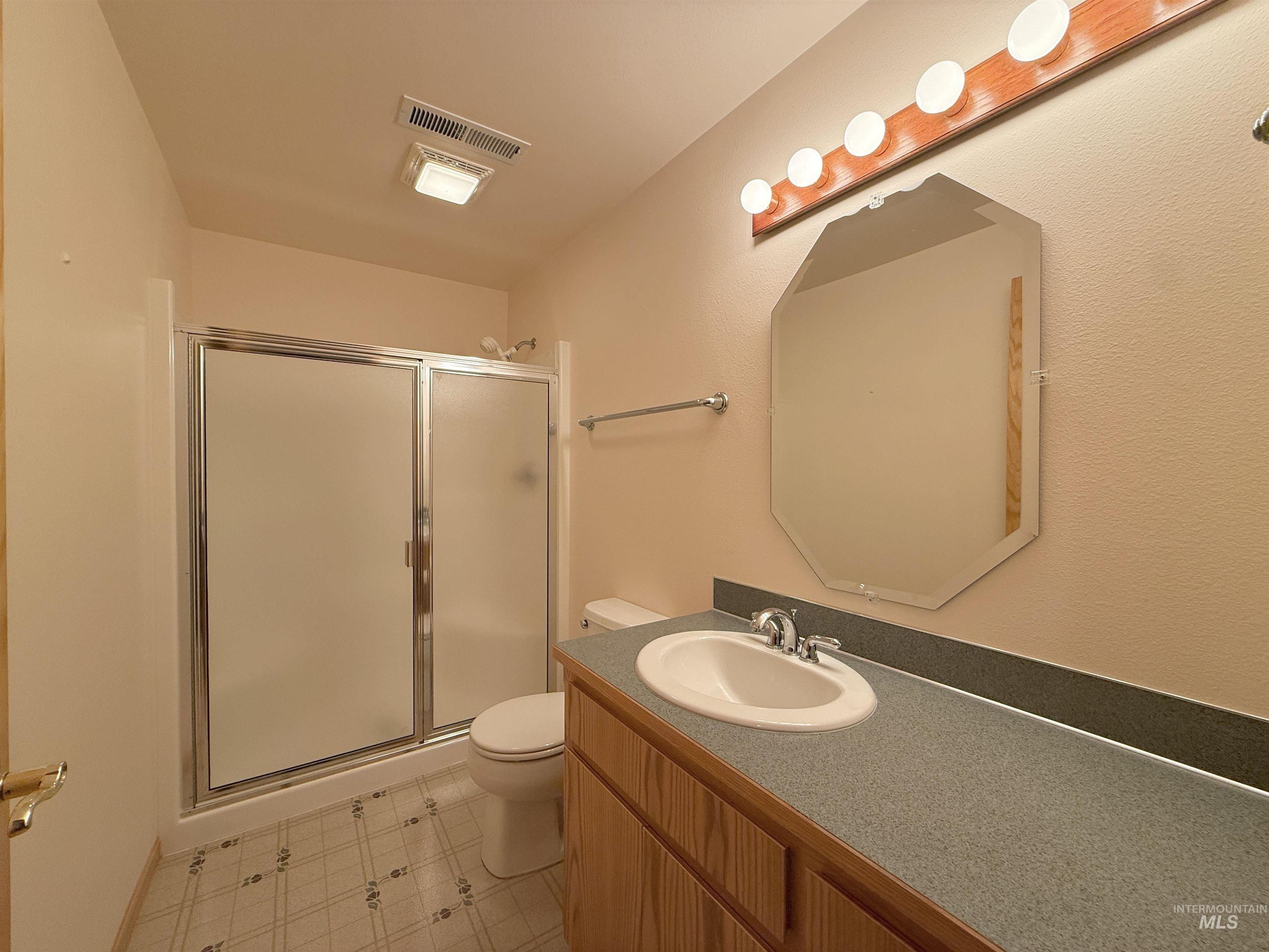 Full bath featuring a shower stall, vanity, and tile patterned floors