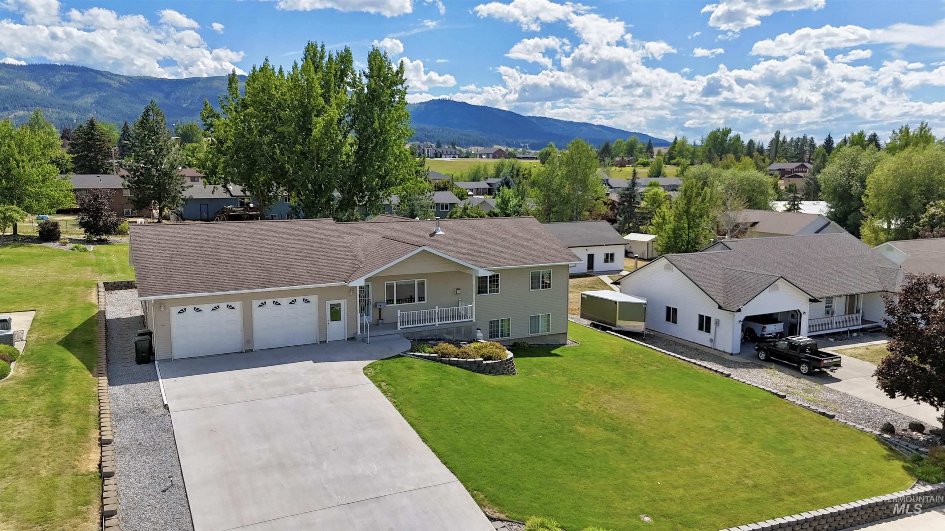 View of front of property with concrete driveway, a mountain view, a residential view, roof with shingles, and a garage