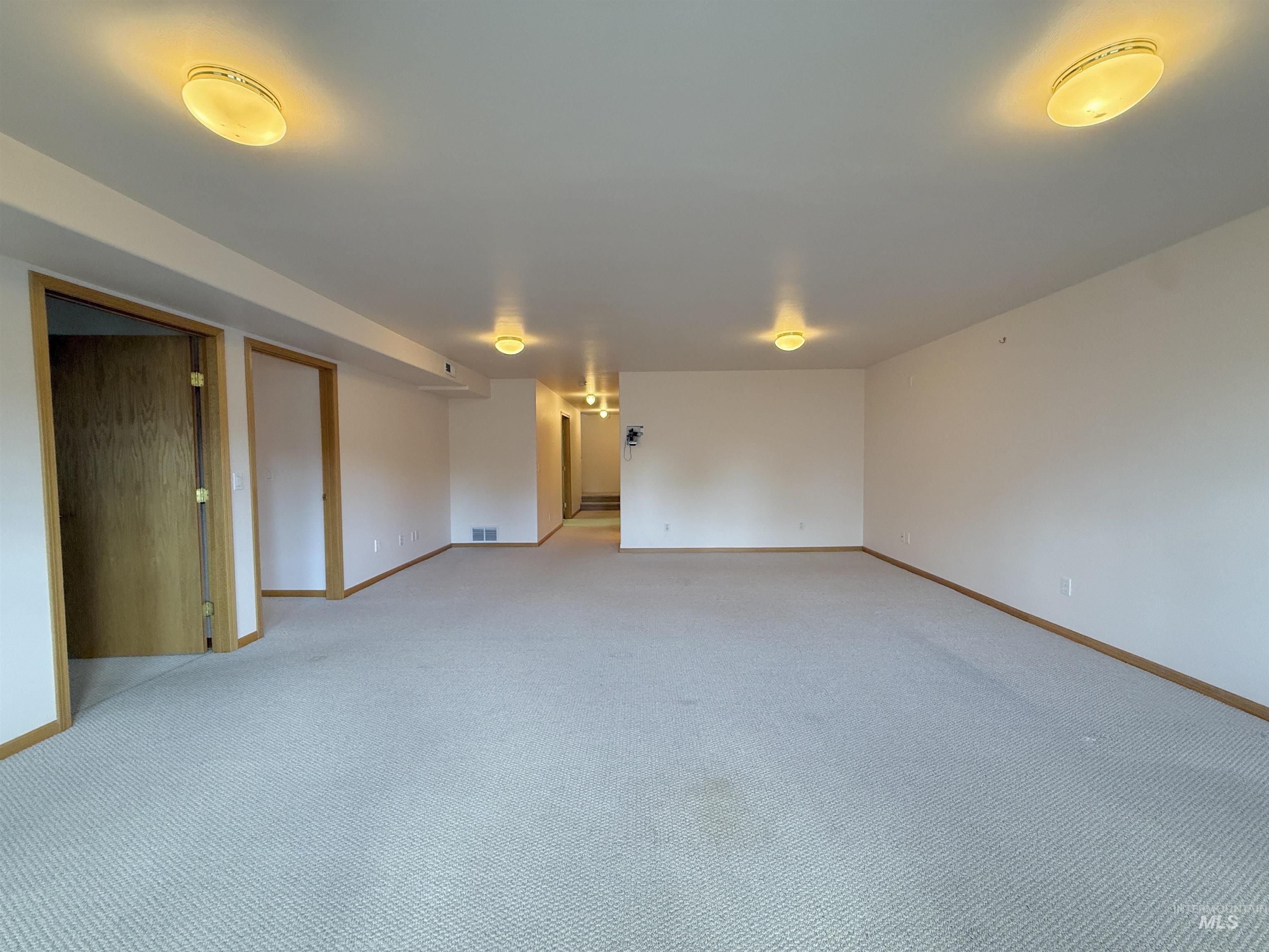 Empty room featuring light colored carpet and baseboards
