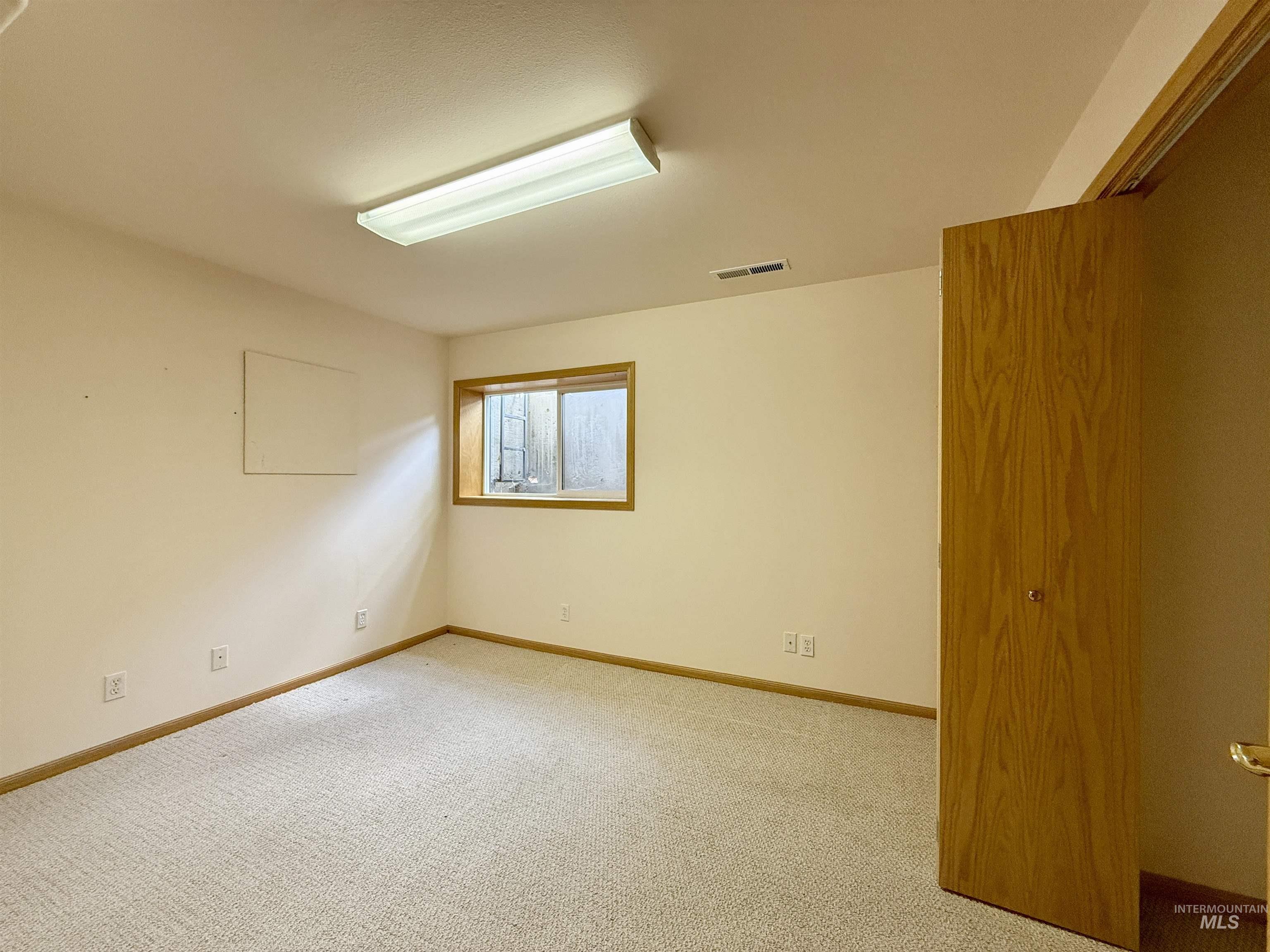 Spare room featuring carpet and baseboards