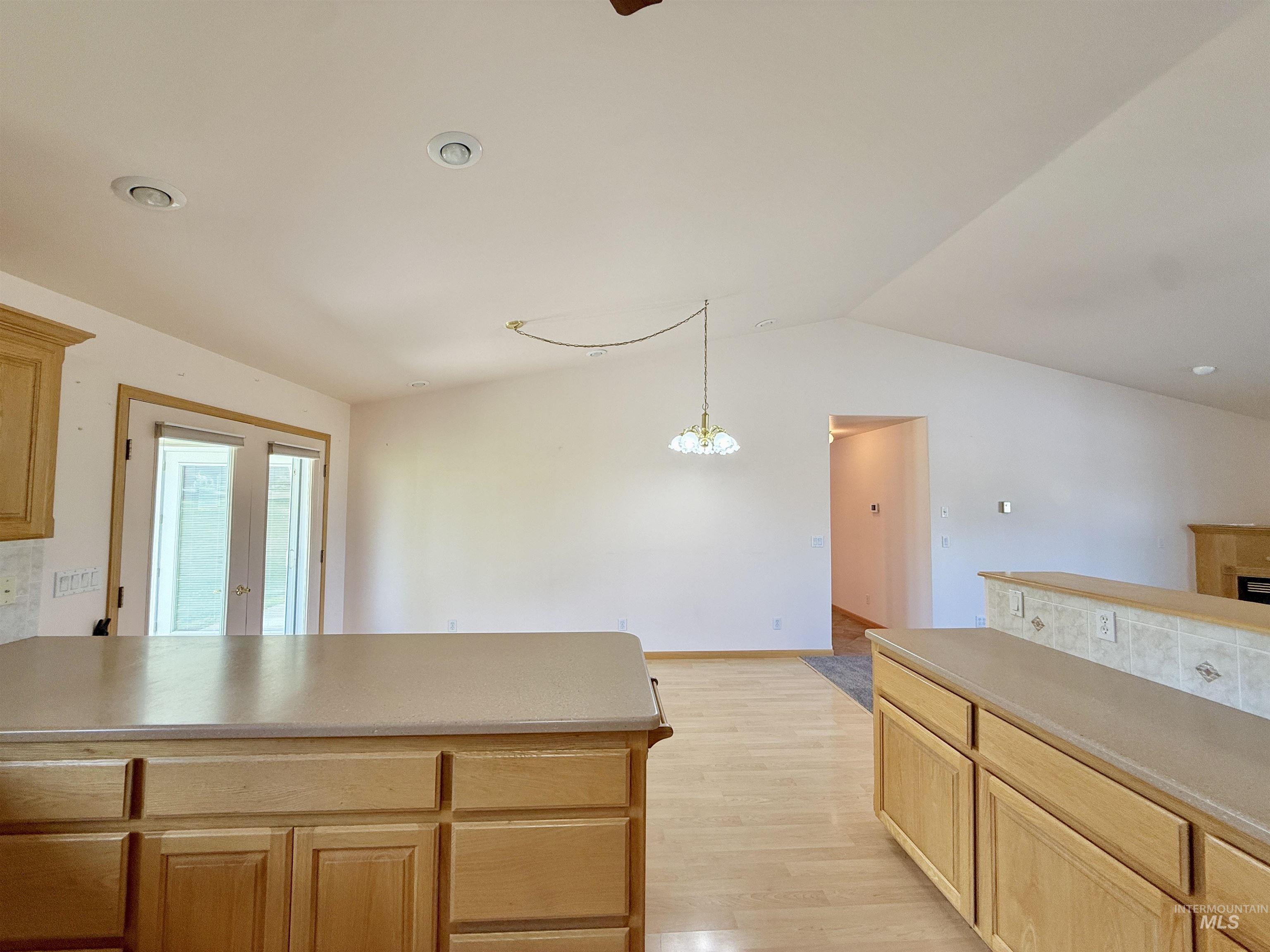 Kitchen with light wood-style floors, lofted ceiling, recessed lighting, a peninsula, and light brown cabinets